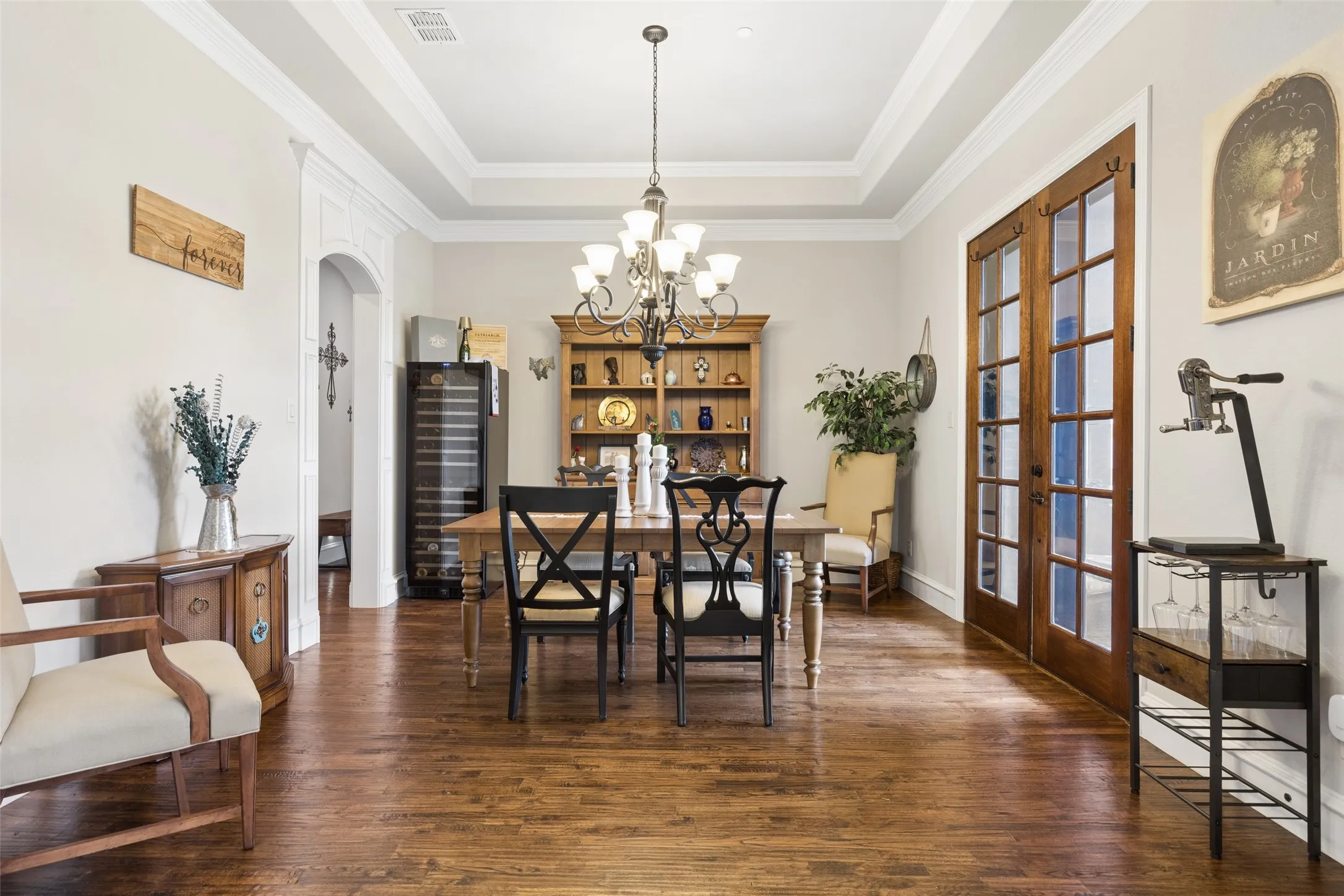 Dining space featuring wood-finish flooring, a coffered ceiling, a chandelier light fixture, and double glass-paneled doors