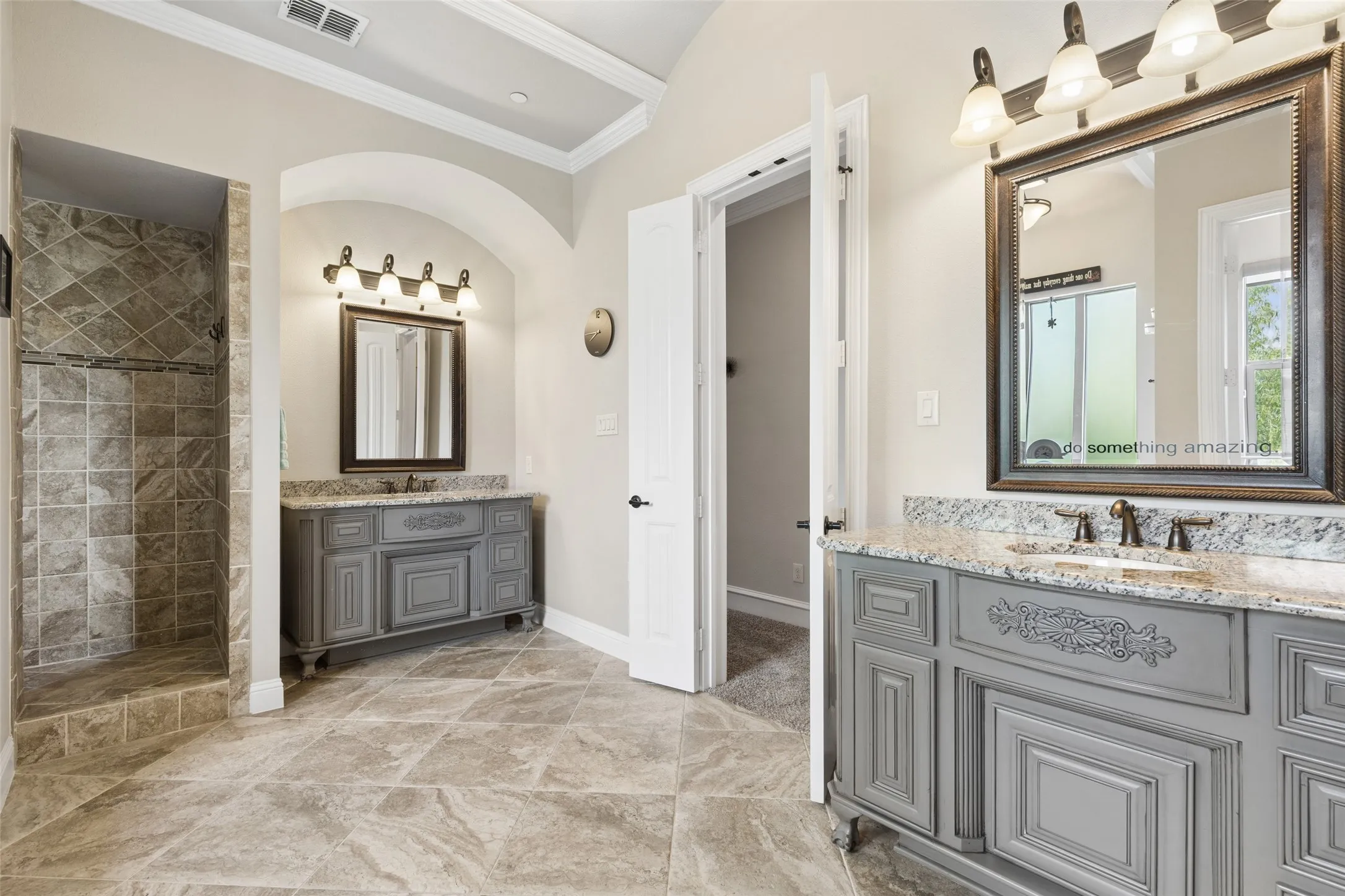 Dual vanity bathroom featuring gray custom cabinetry, light-toned granite countertops, and tile flooring