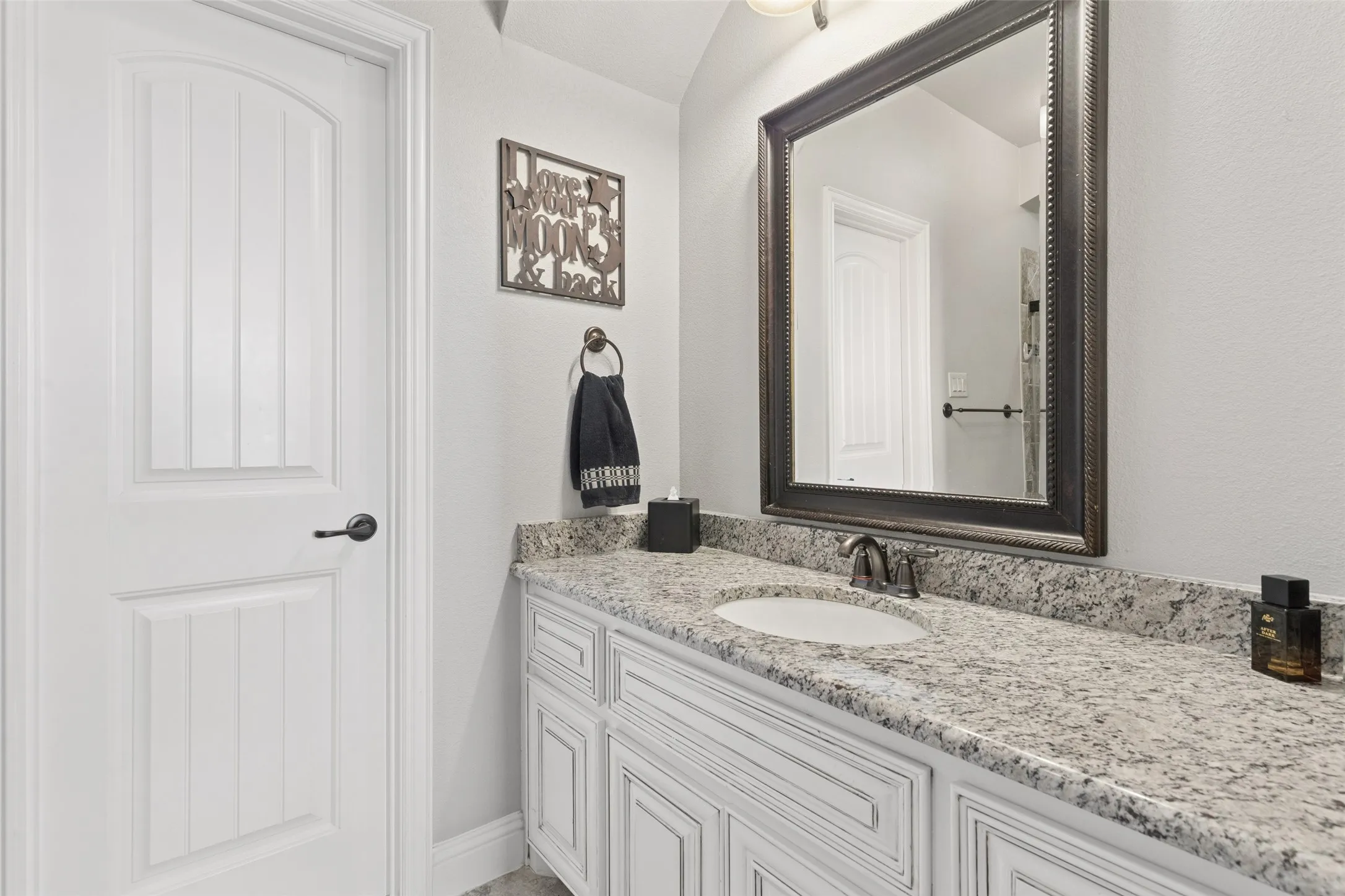 Bathroom vanity featuring a speckled countertop, undermount sink, and dark bronze faucet