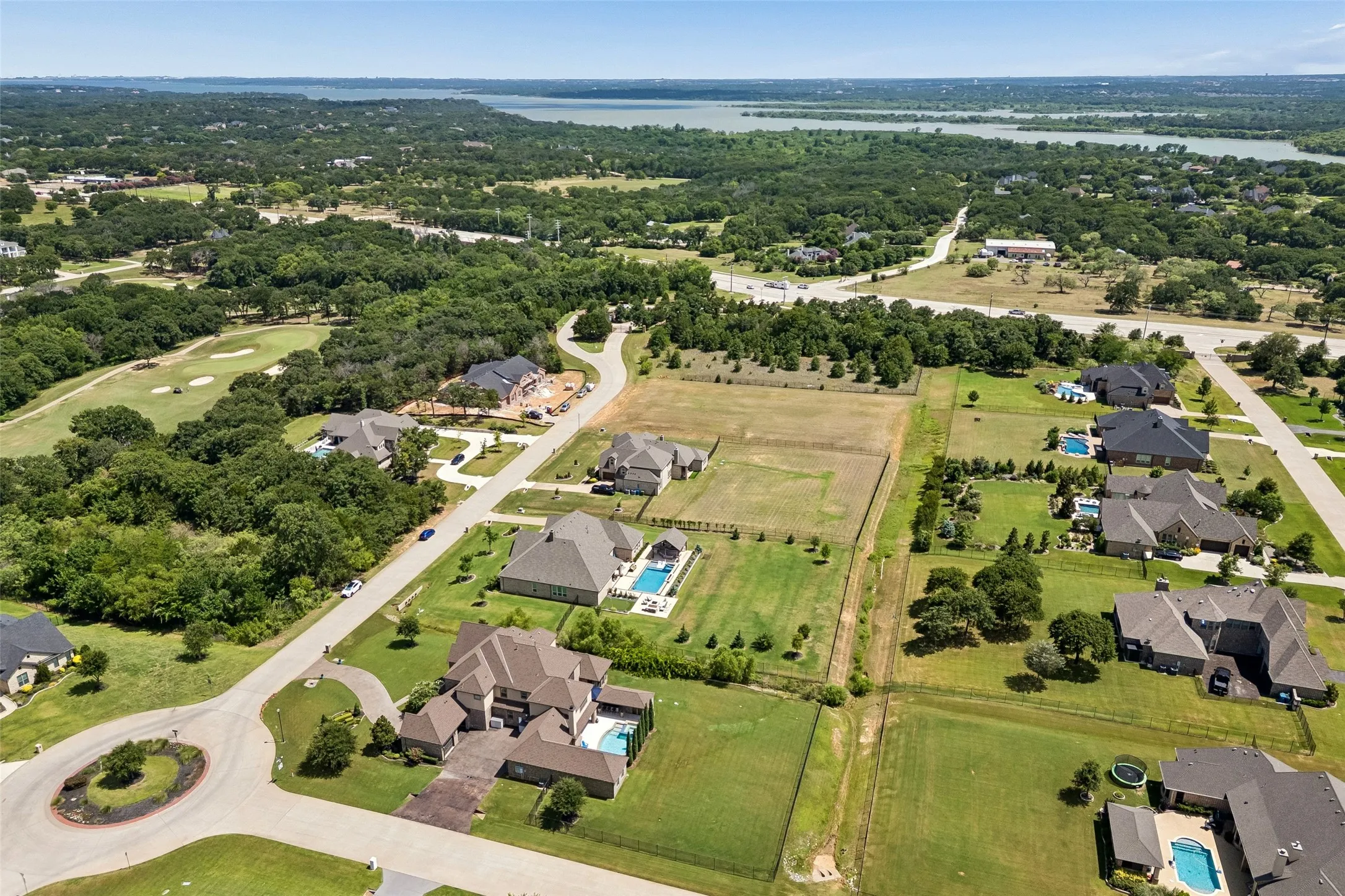 Expansive residential development featuring large lots, mature trees, and a distant body of water