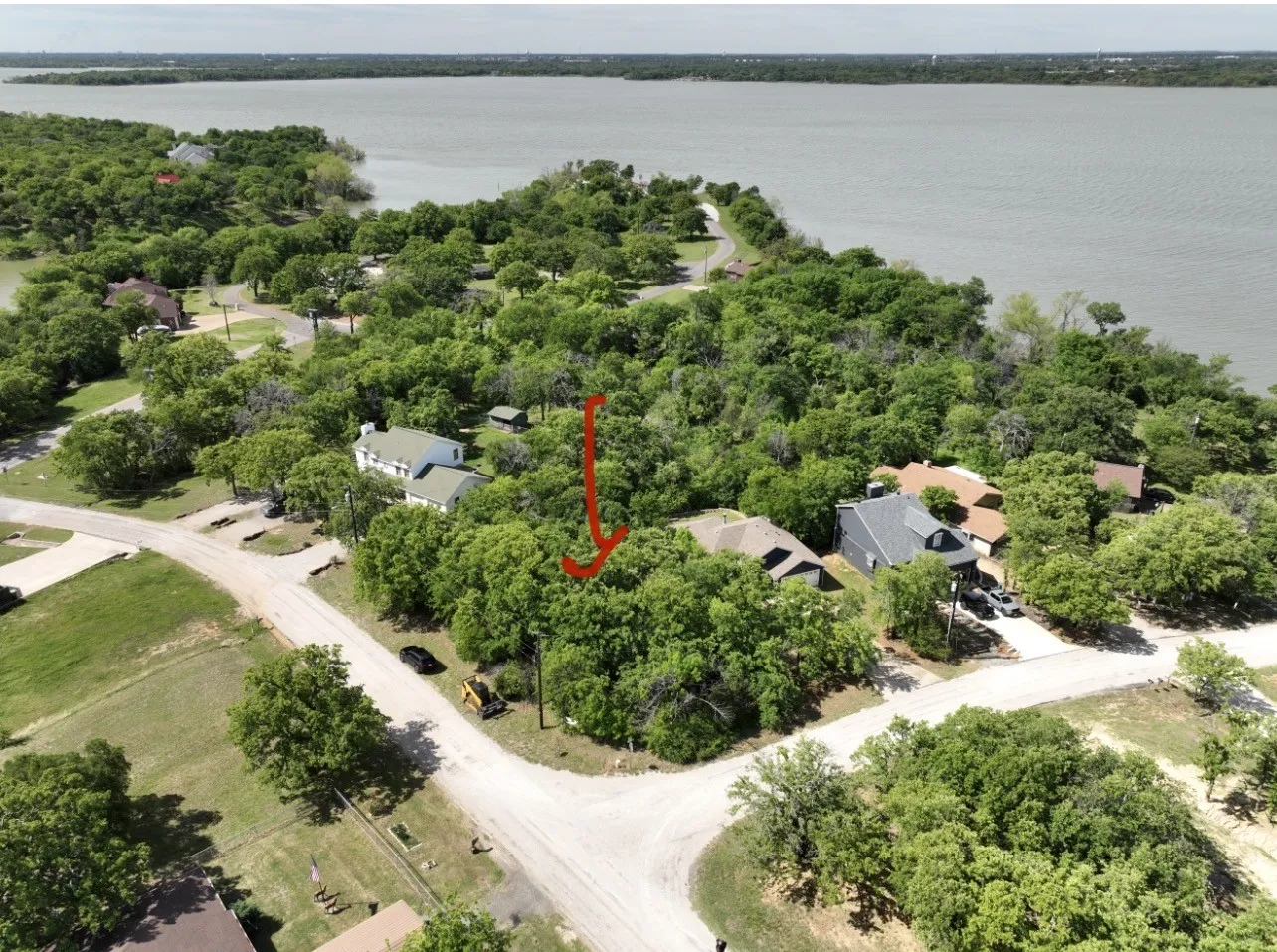 Aerial perspective showcasing a residential area with extensive tree coverage and proximity to a large body of water