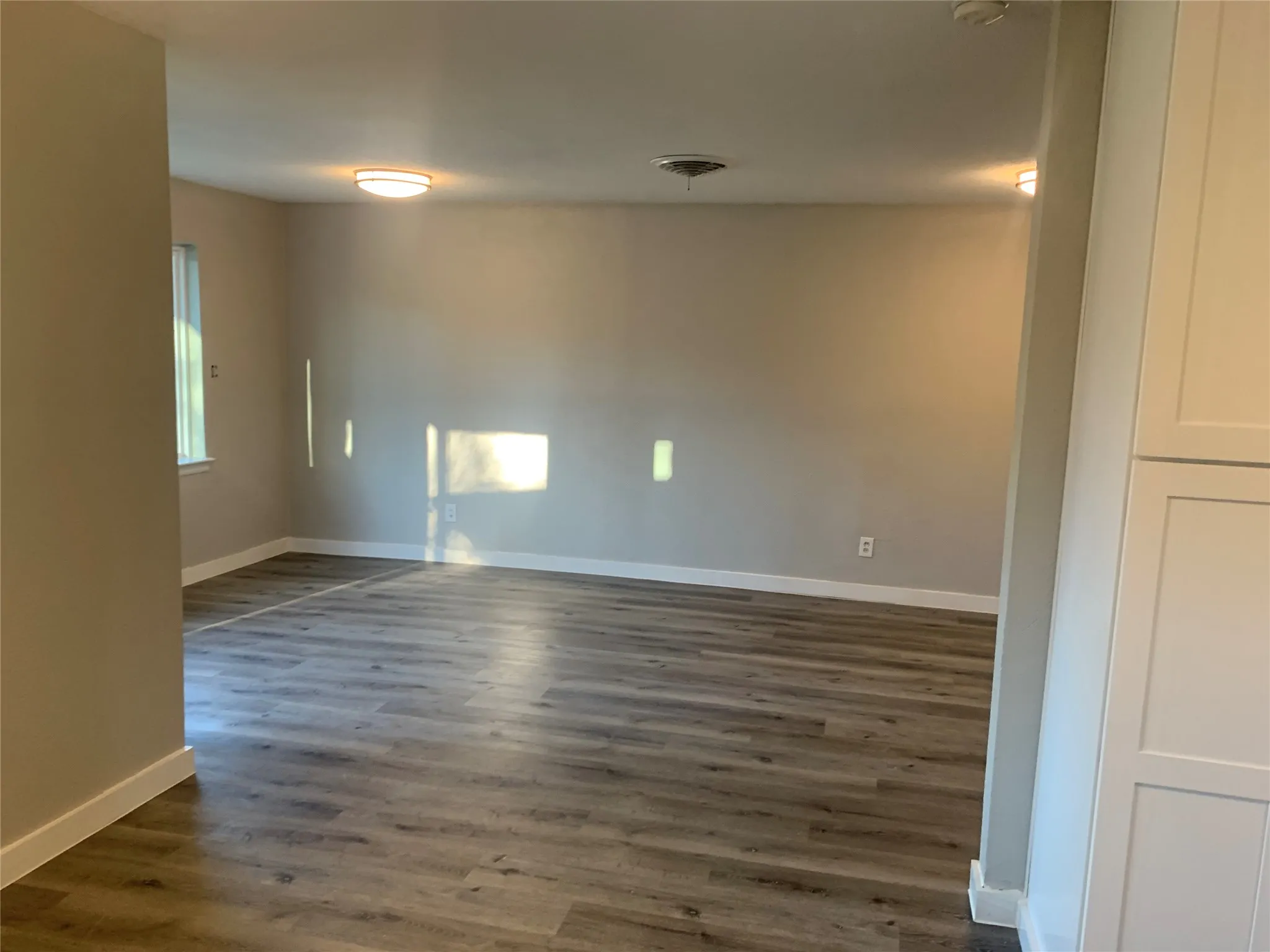 Open concept living area with wood-finish flooring, neutral wall tones, and white baseboards