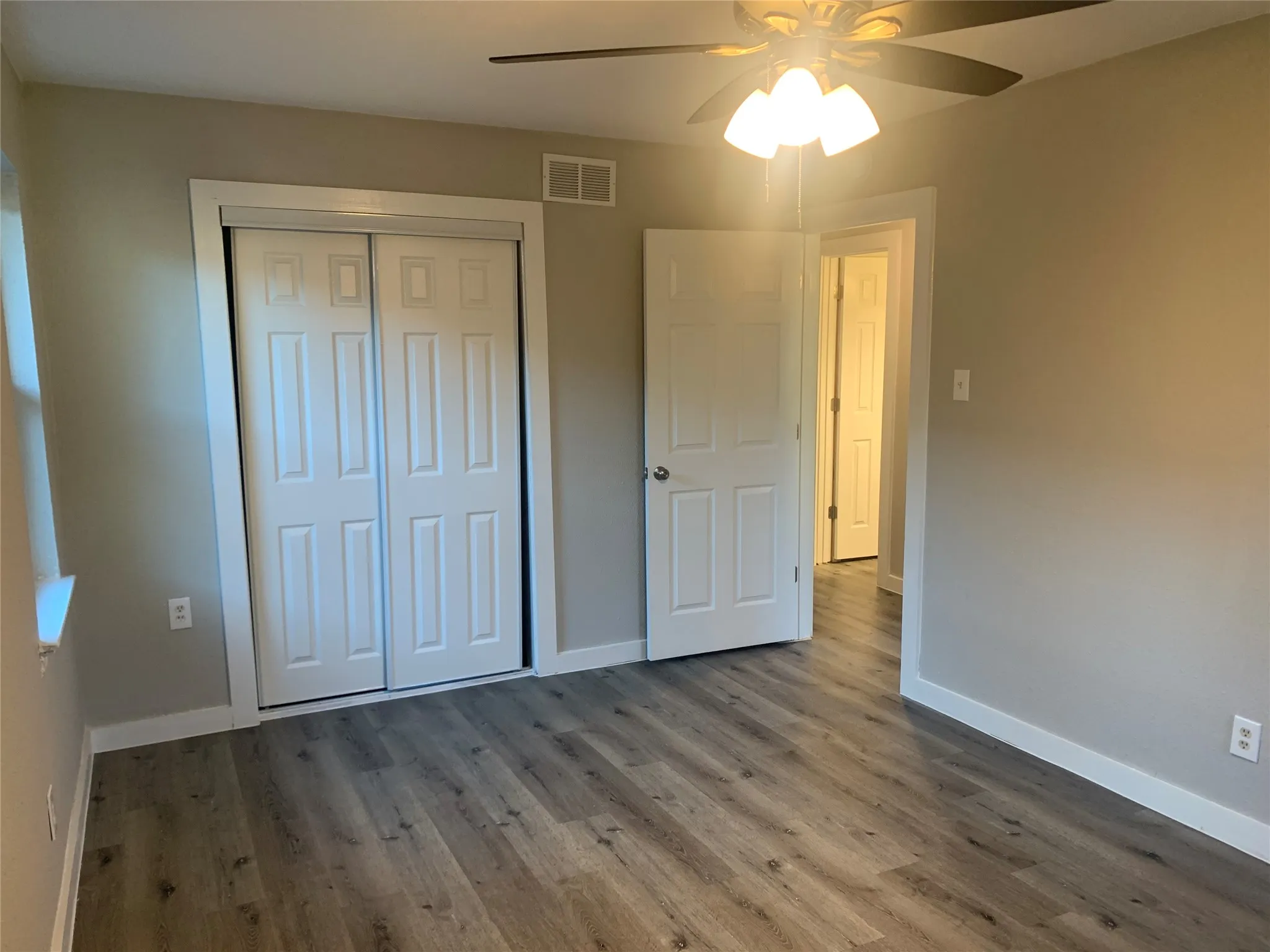 Room featuring wood-finish flooring, neutral wall tones, a ceiling fan with integrated lighting, and a closet with bifold​​‌​​​​‌​​‌‌​‌‌​​​‌‌​‌​‌​‌​​​‌​​ doors