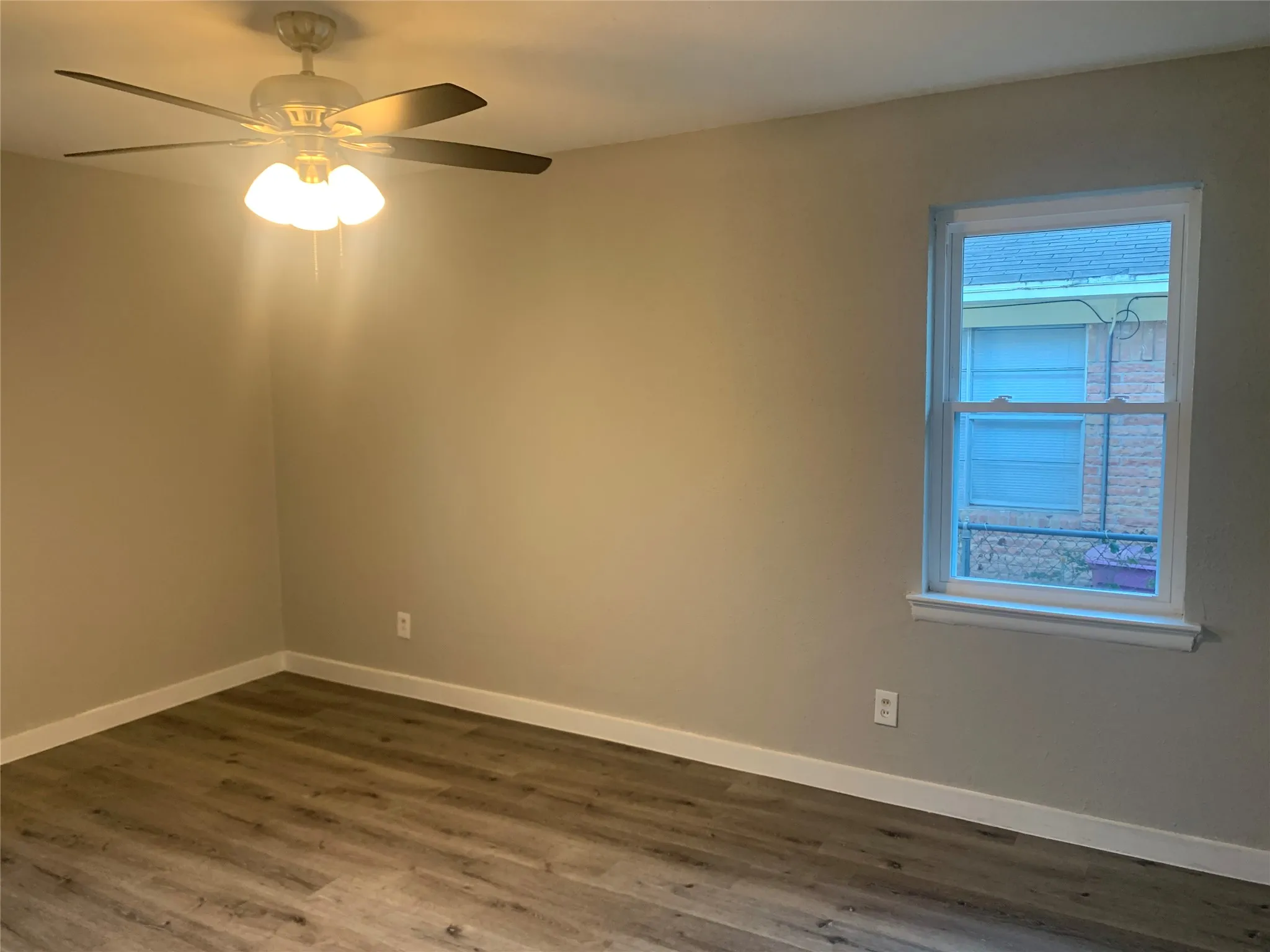 Room with wood-finish flooring, neutral wall tones, and white baseboards