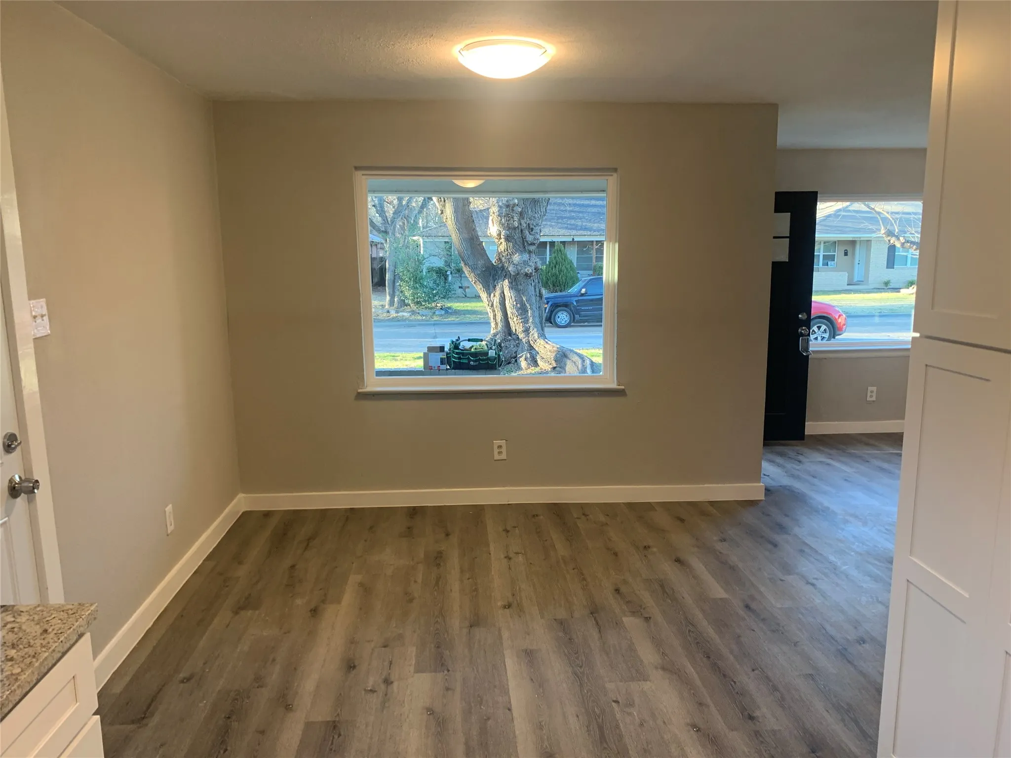Spacious interior featuring wood-finish flooring, a large window, neutral wall tones, and white baseboards