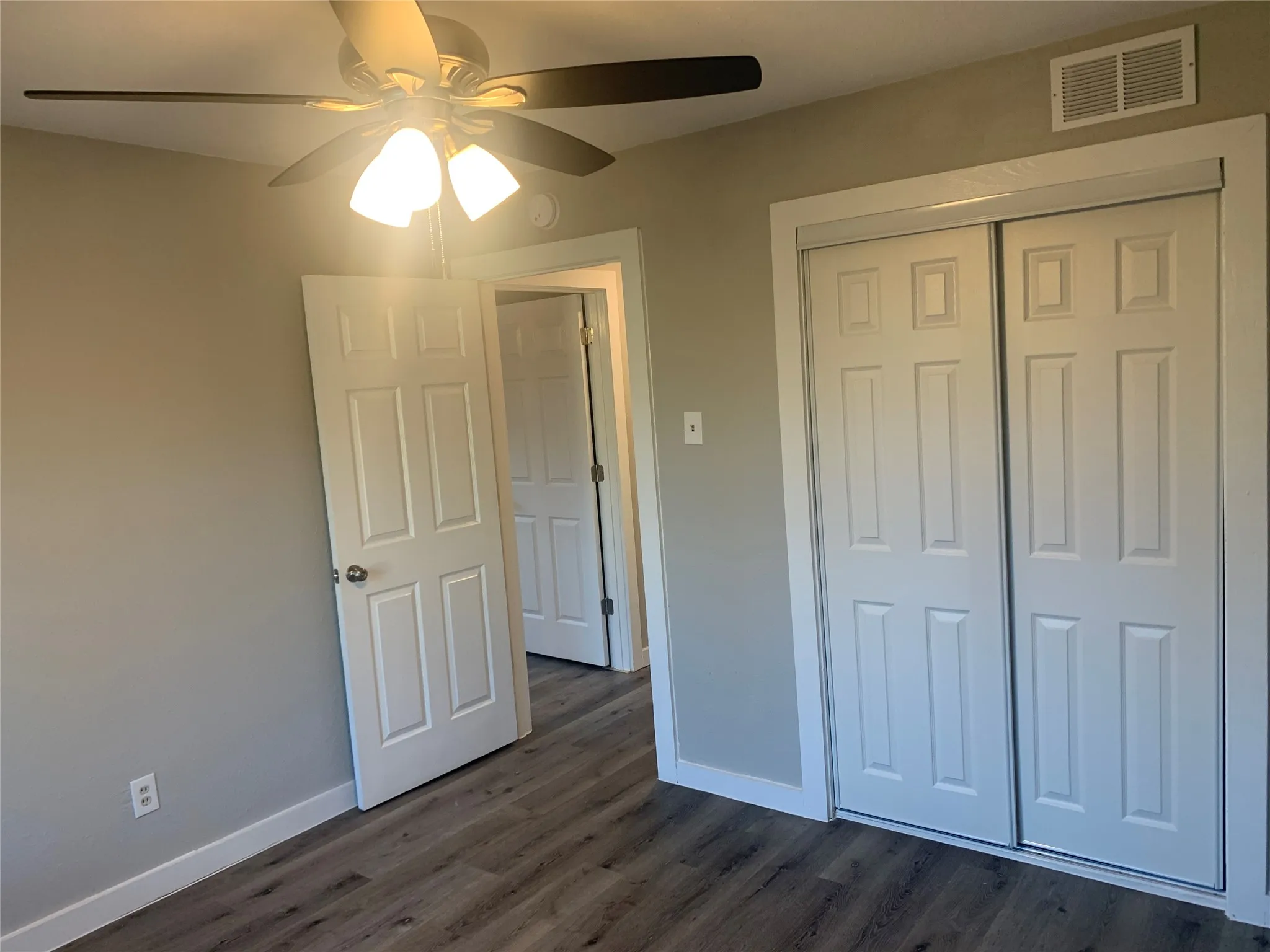 Room featuring wood-finish flooring, neutral wall tones, and white trim