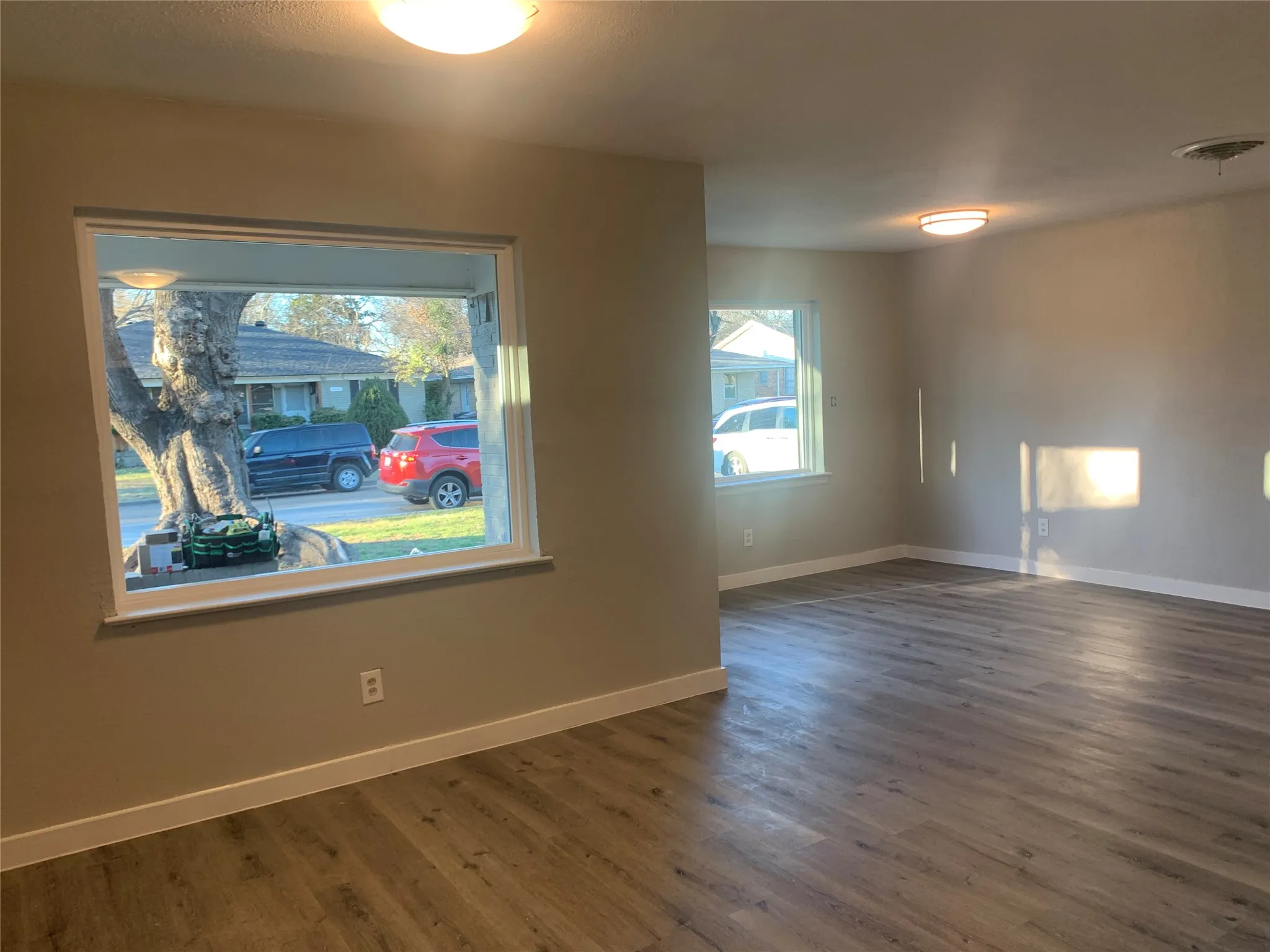 Spacious room featuring wood-finish flooring, neutral paint palette, and white trim