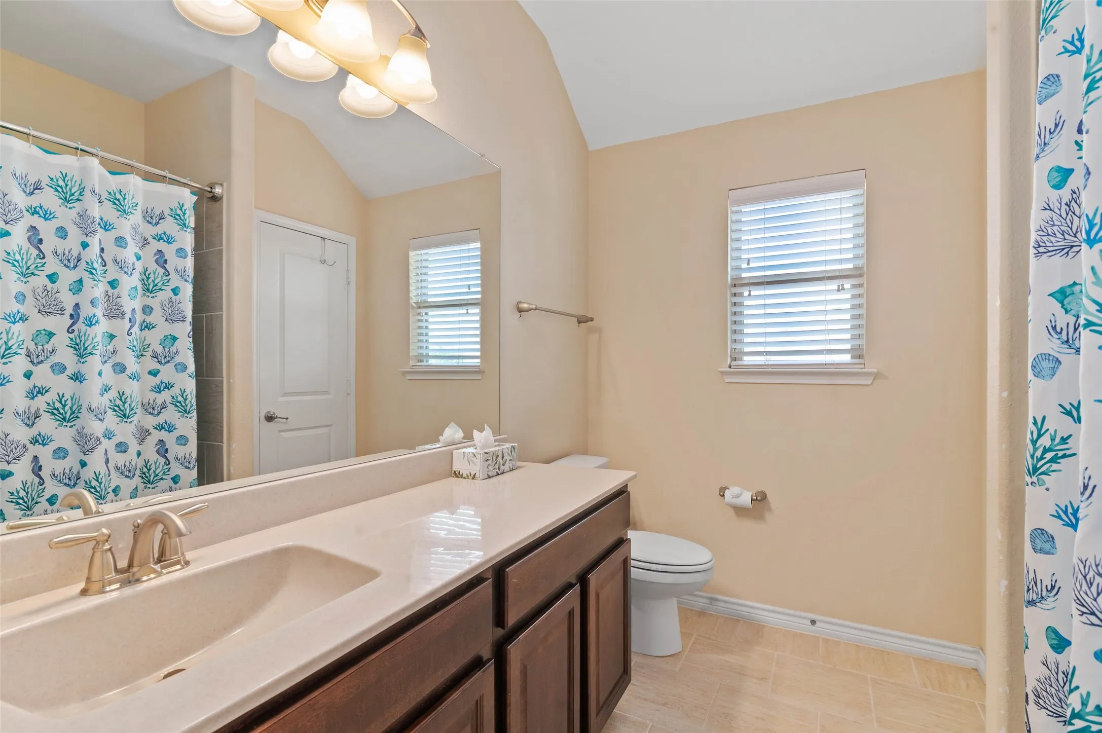 Bathroom featuring a single vanity with a solid surface countertop, integrated sink, and wood-finish cabinetry
