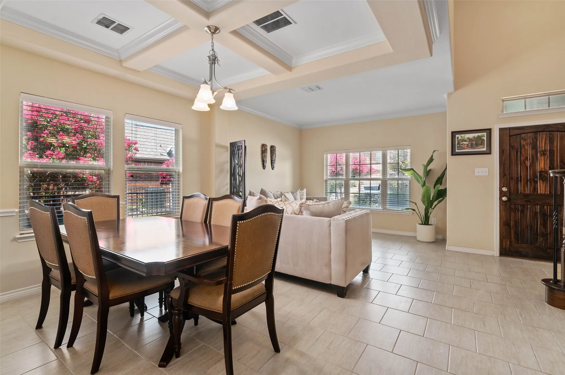 Open-concept dining and living area featuring high ceilings, a tray ceiling detail with a chandelier, and light-toned tile flooring