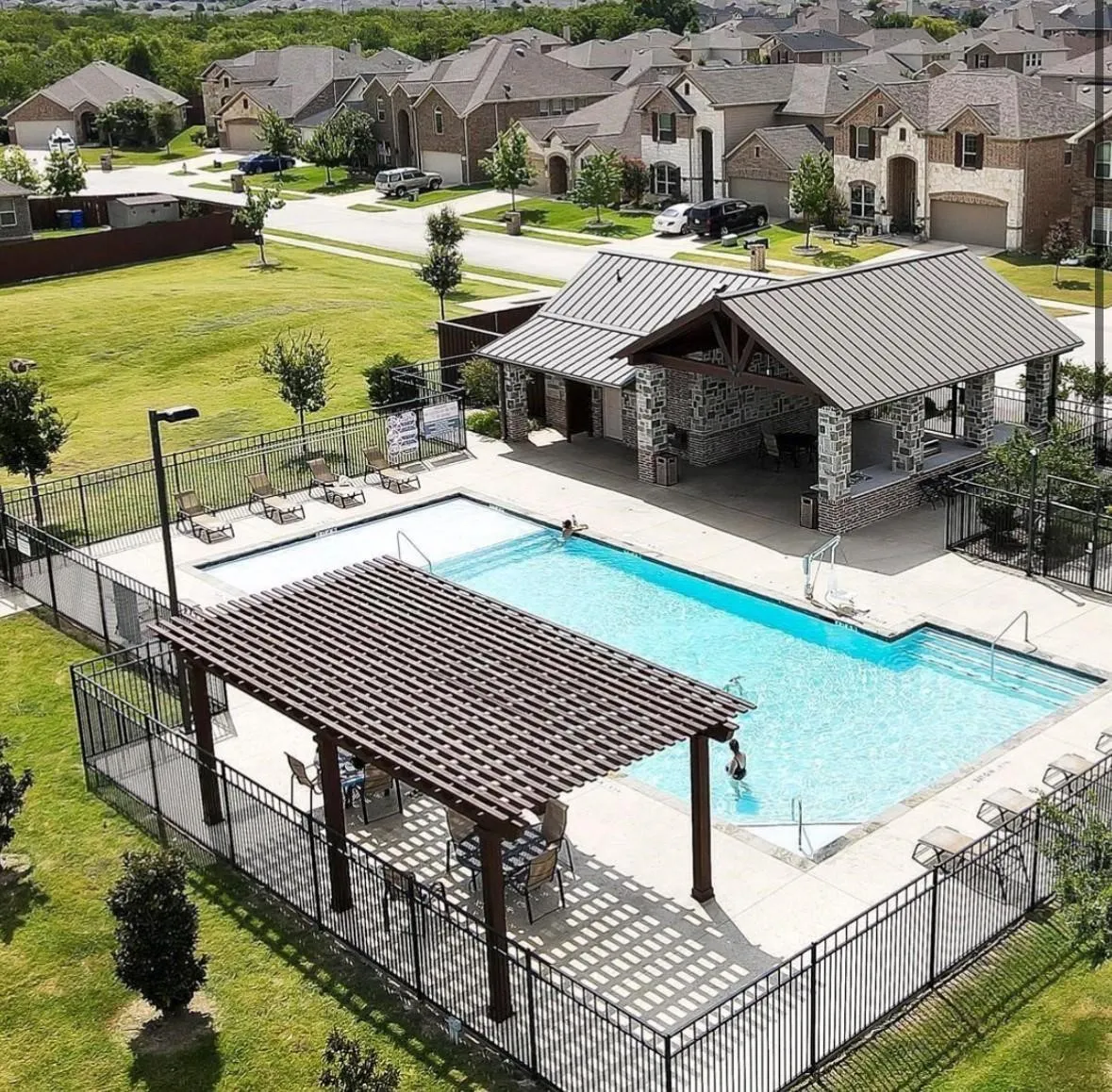 Community swimming pool with an adjacent covered pavilion featuring stone and brick accents