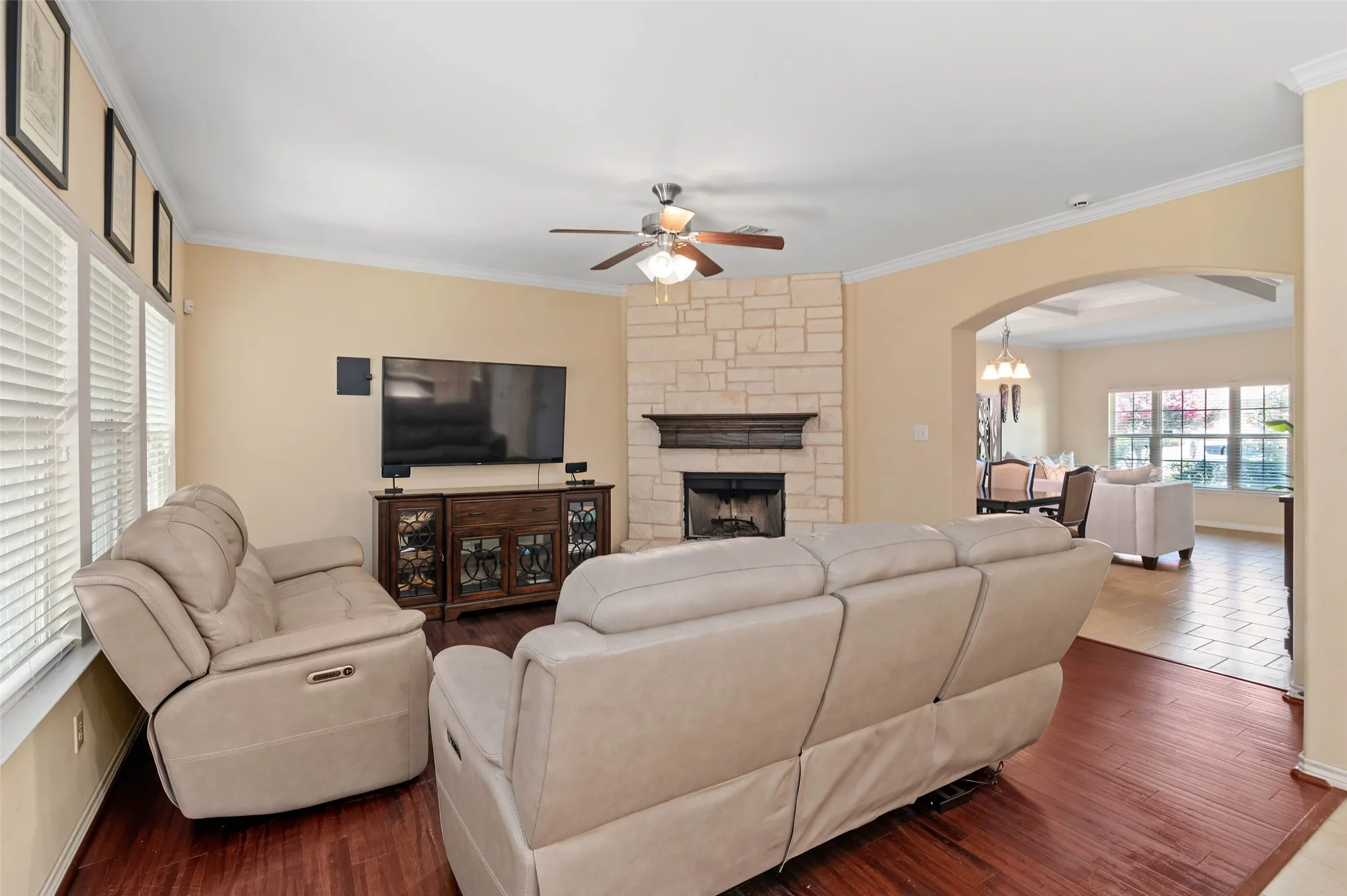 Living room featuring wood-finish flooring and a stone-clad fireplace with a dark wood mantel