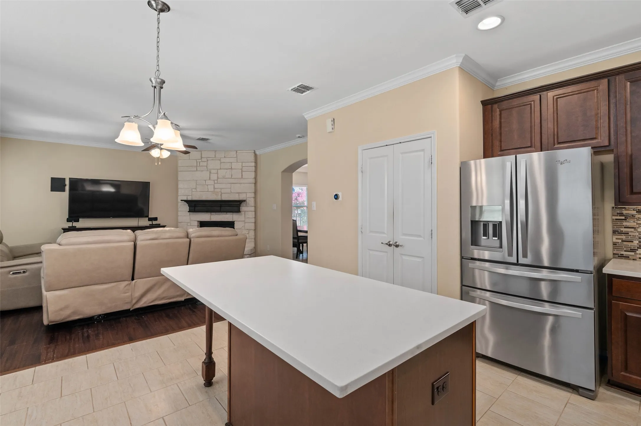 Kitchen island with white countertop, dark wood cabinetry, and integrated electrical outlet
