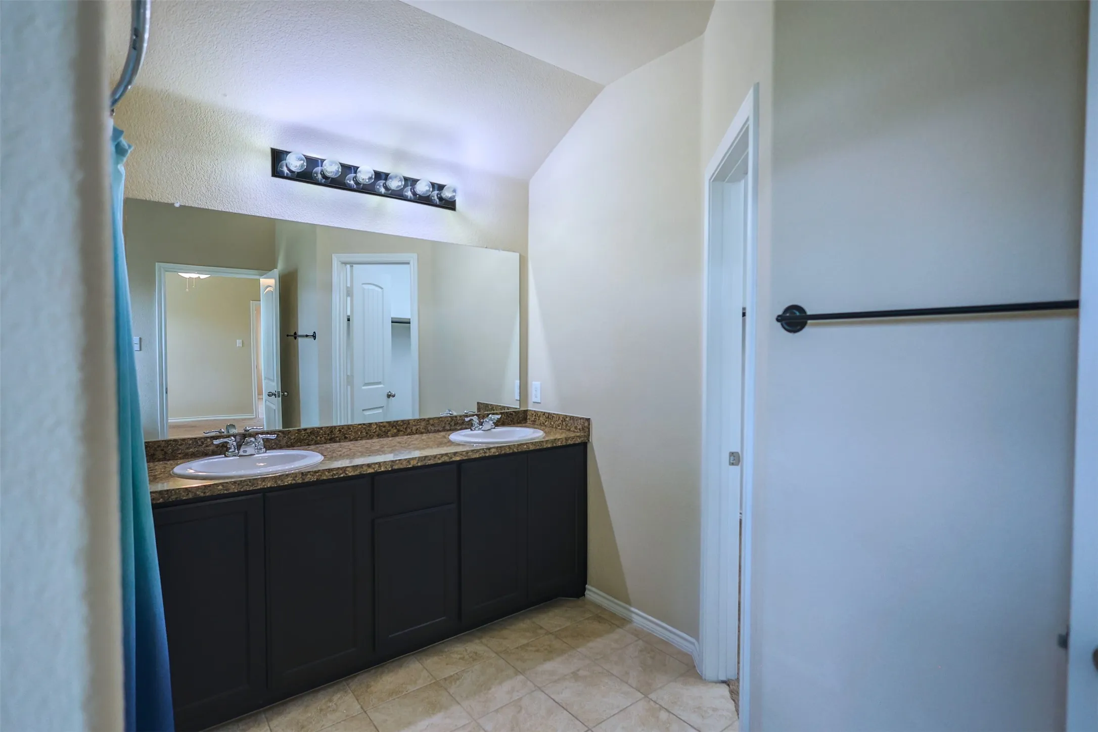 Double vanity featuring dark cabinetry, dual undermount sinks, and a speckled countertop