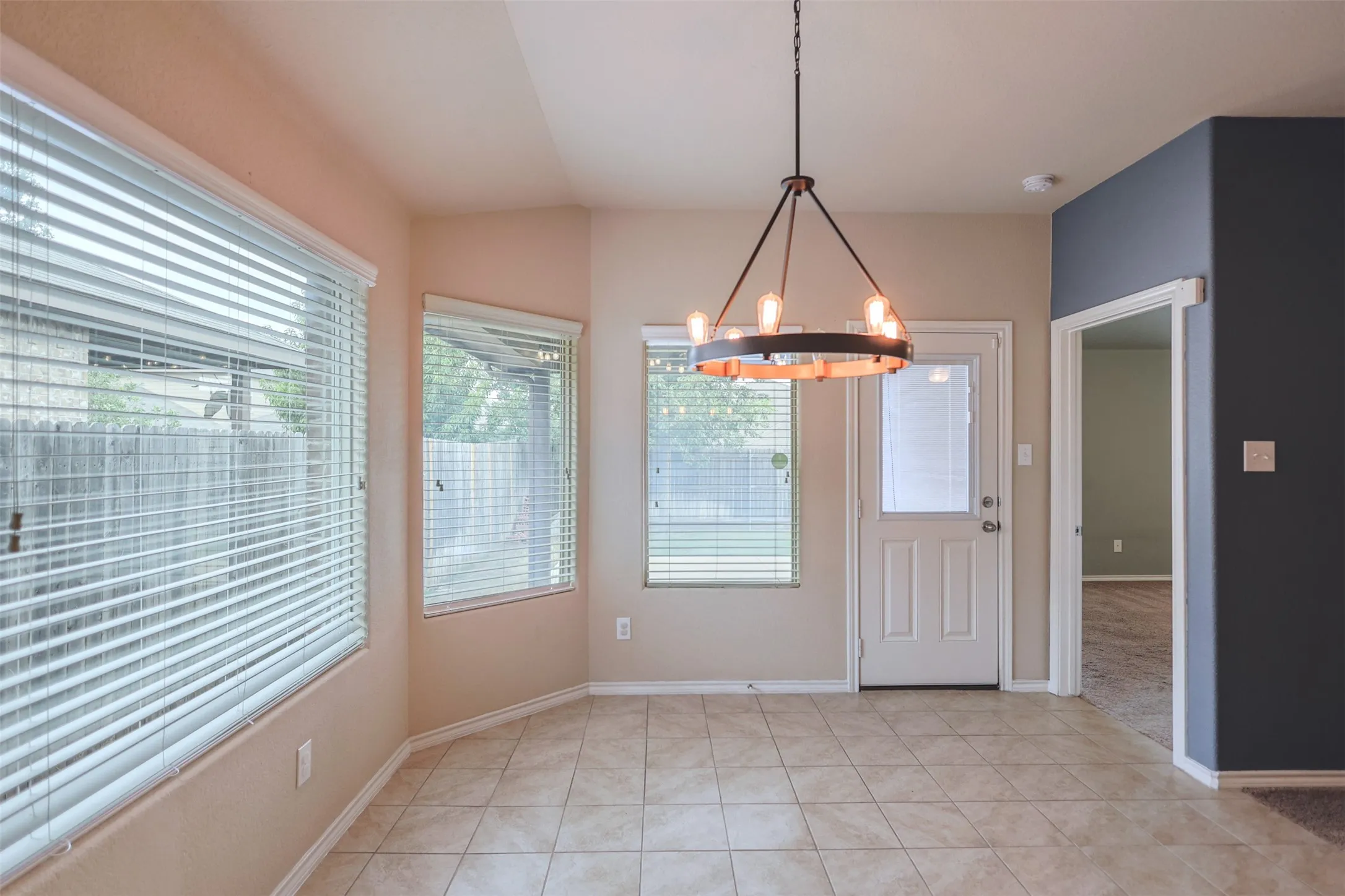 Dining area featuring a contemporary chandelier, multiple windows, a white paneled door with glass insert, and tile flooring