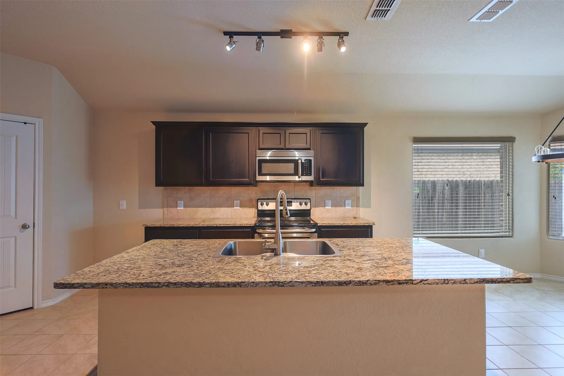 Massive Kitchen Work island / breakfast bar, featuring an upgraded dual-basin stainless steel sink and a granite countertop!
