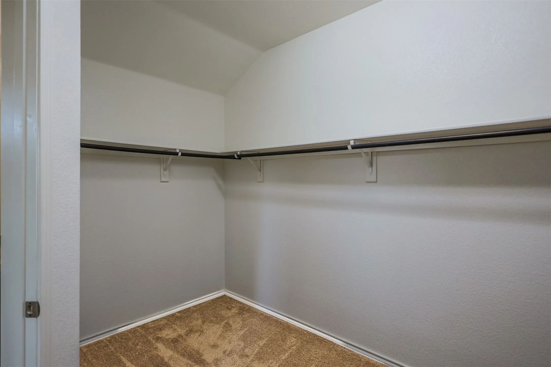 Spacious walk-in closet featuring white walls, a single-track clothes rod, and an upper shelf
