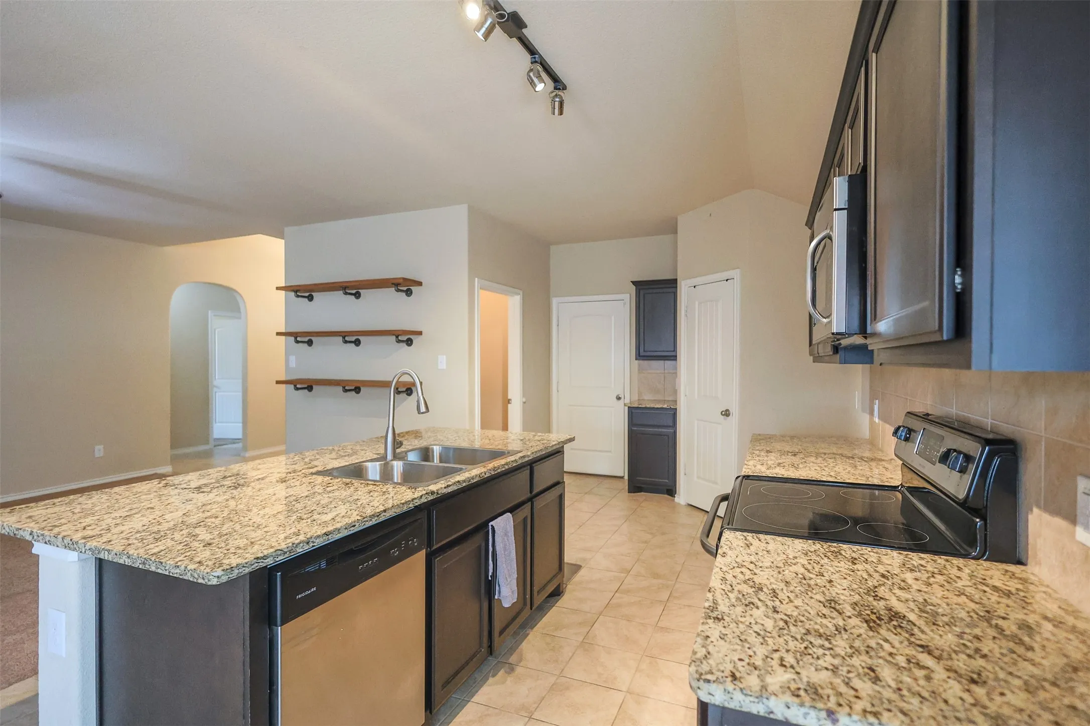 Kitchen featuring an island with double basin sink, stainless steel dishwasher, and granite countertops