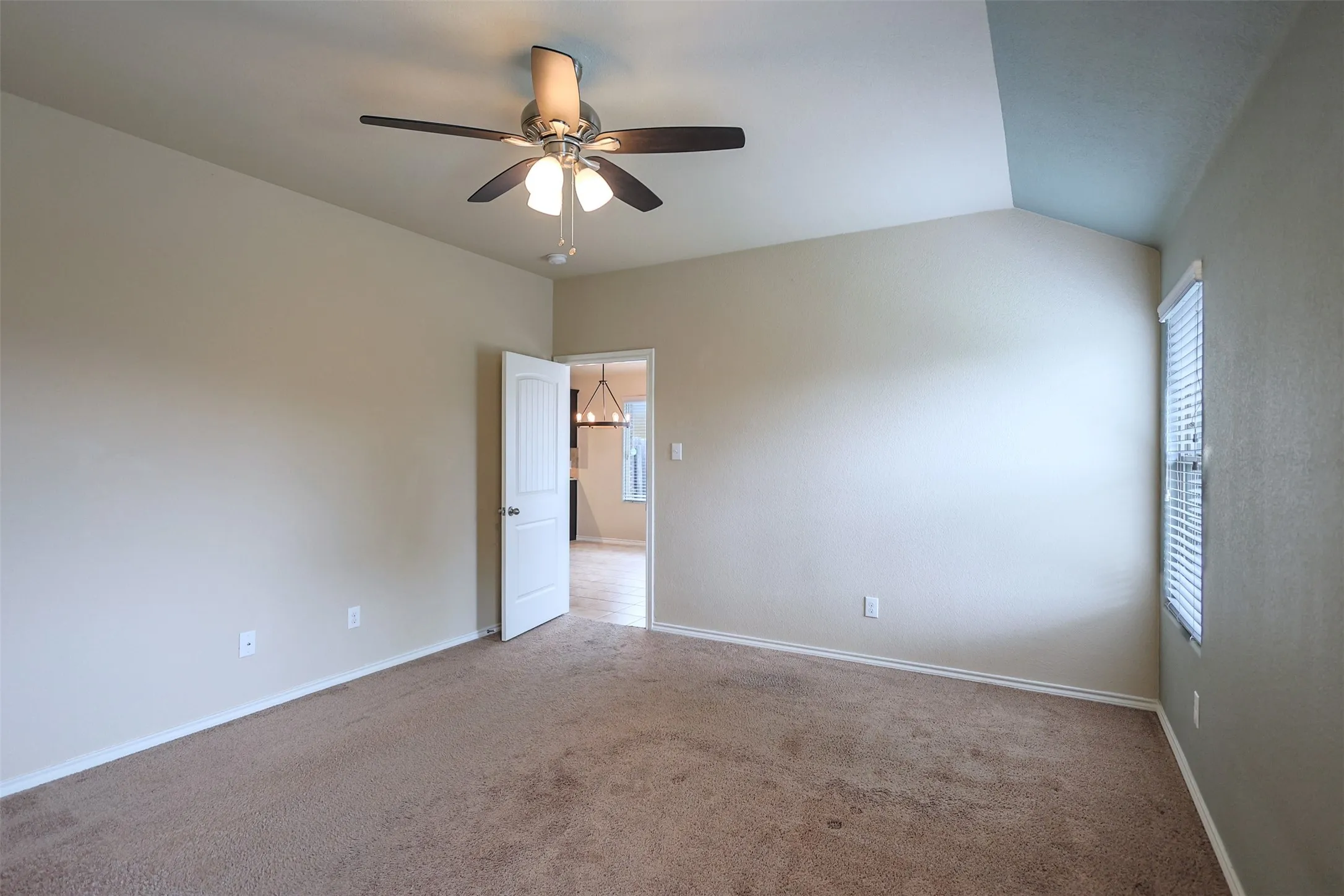 Large Bedroom featuring vaulted ceilings, a ceiling fan with integrated lighting, carpet flooring, and a single window with blinds