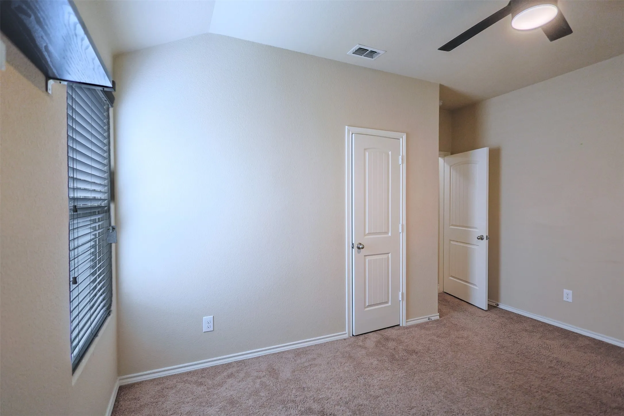 Carpeted room featuring a vaulted ceiling and a ceiling fan with integrated lighting