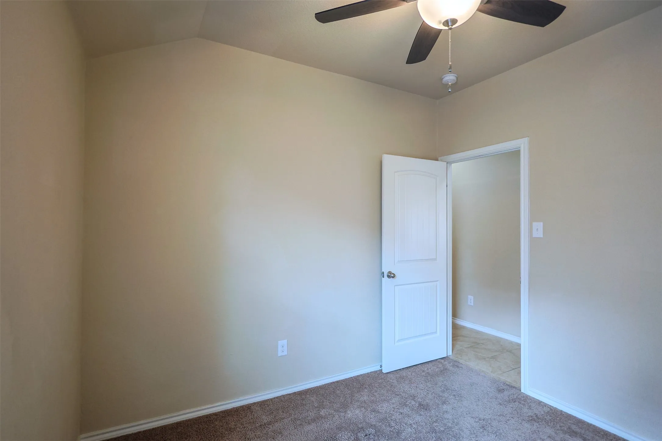 Carpeted room featuring a ceiling fan with light fixture, neutral wall paint, and white trim