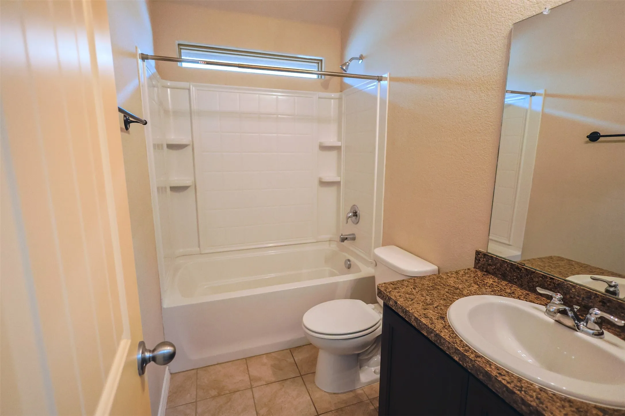 Bathroom featuring a tub/shower combination, dark vanity with a light-toned countertop, and square tile flooring