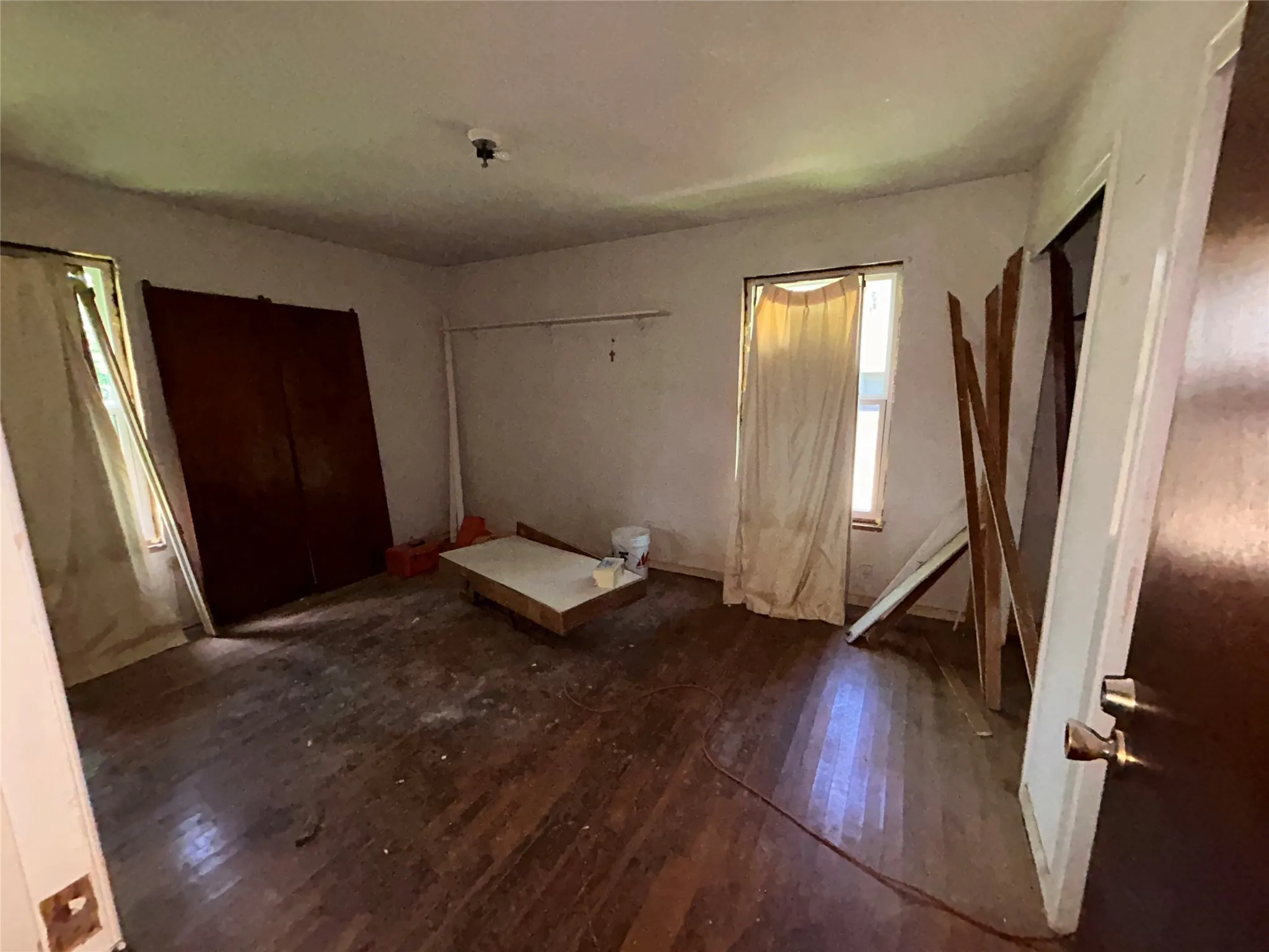 Interior room featuring wood-finish flooring, two window openings, and a ceiling-mounted light fixture