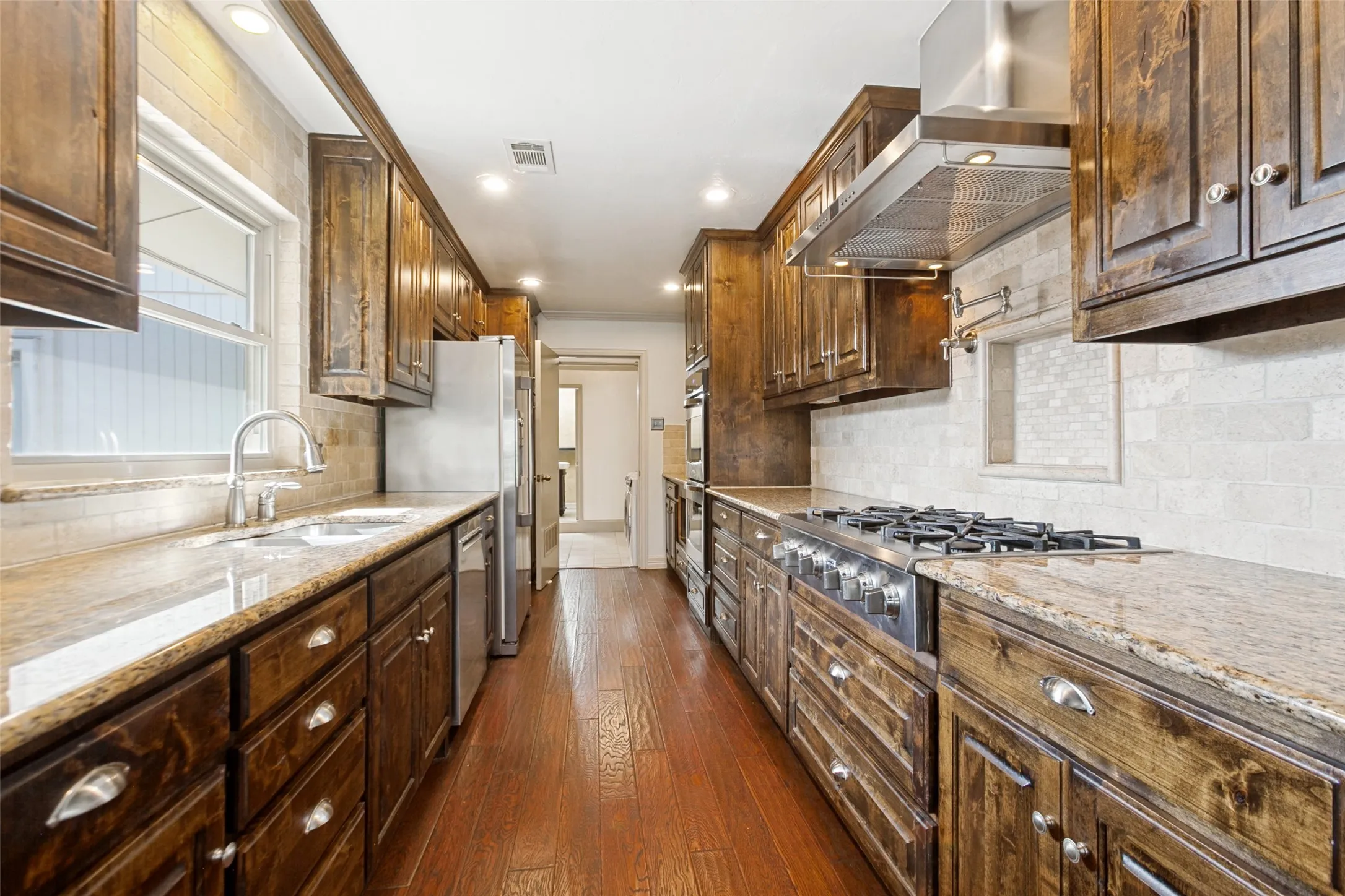Granite counters, 6 burner gas cooktop, Vent hood, double oven, and wine fridge