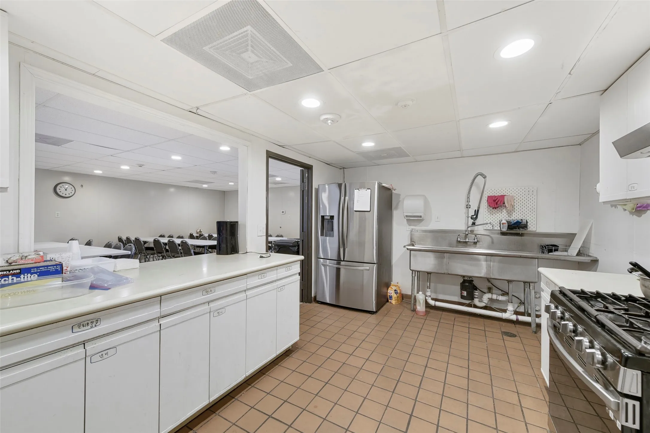 Commercial-style kitchen featuring a stainless steel double basin sink, stainless steel refrigerator, and a gas range