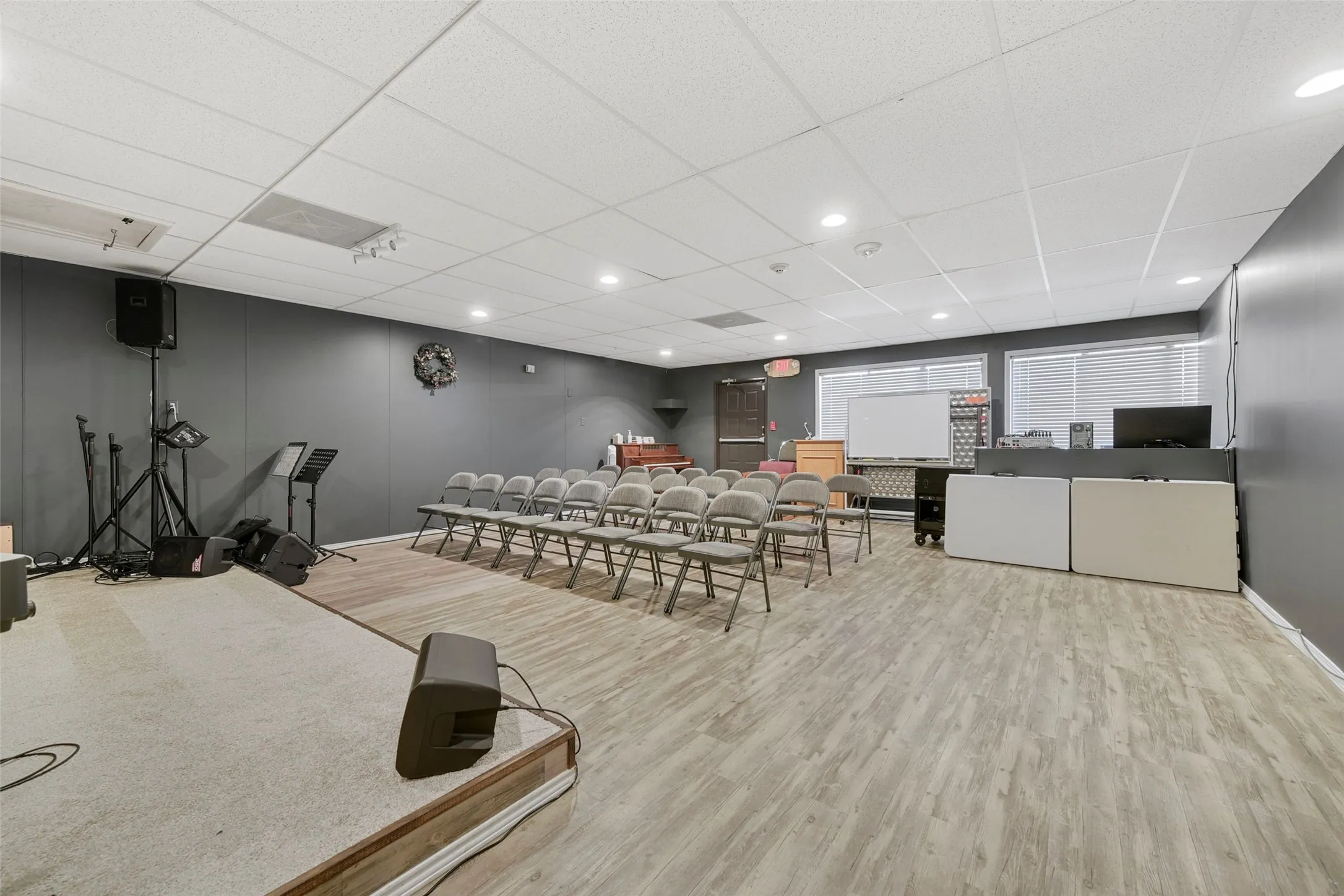 Large open room with a dropped ceiling, recessed lighting, and wood-finish flooring