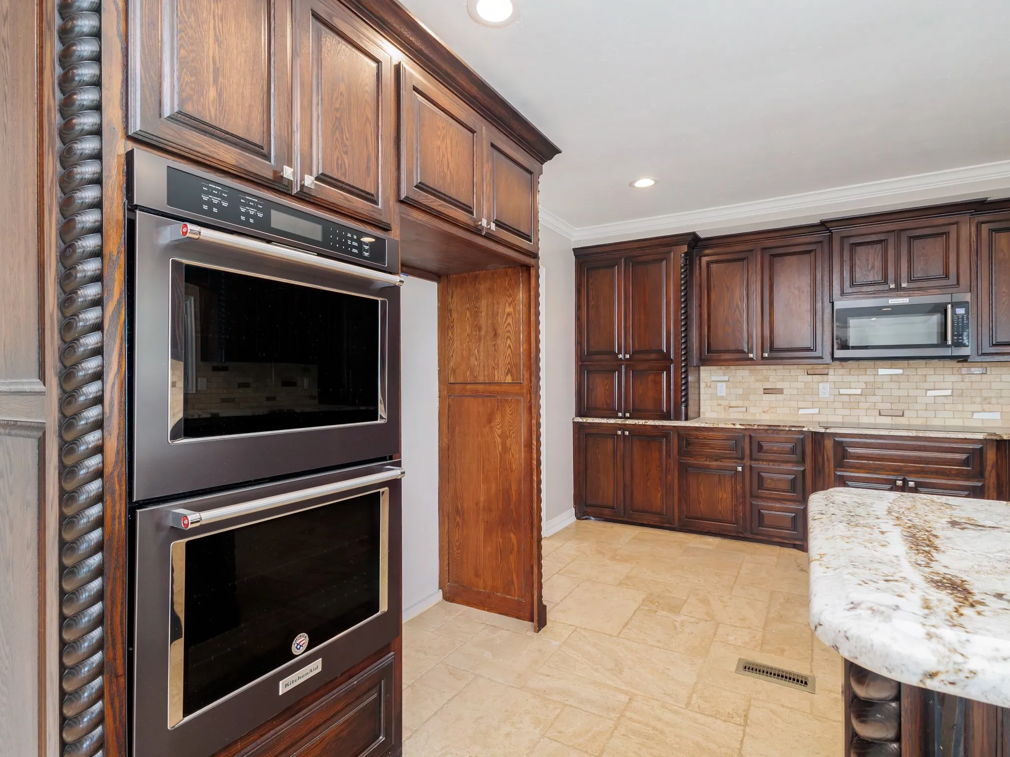 Stainless steel double wall ovens integrated into dark wood cabinetry