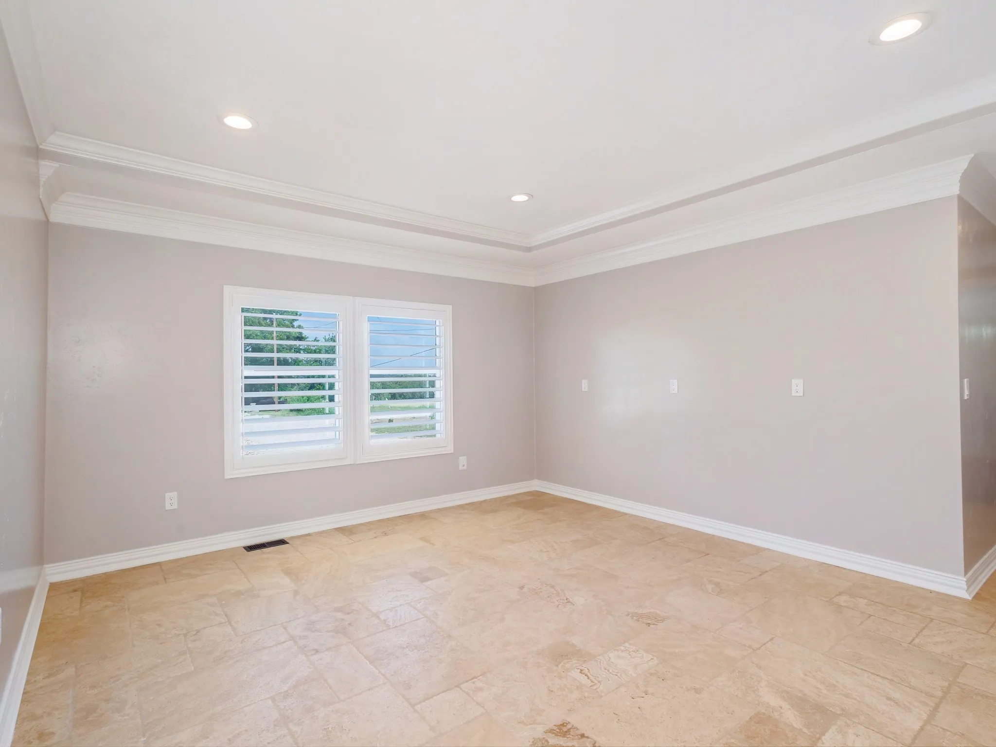 Spacious room featuring neutral wall tones, large format tile flooring, and a tray ceiling with recessed lighting