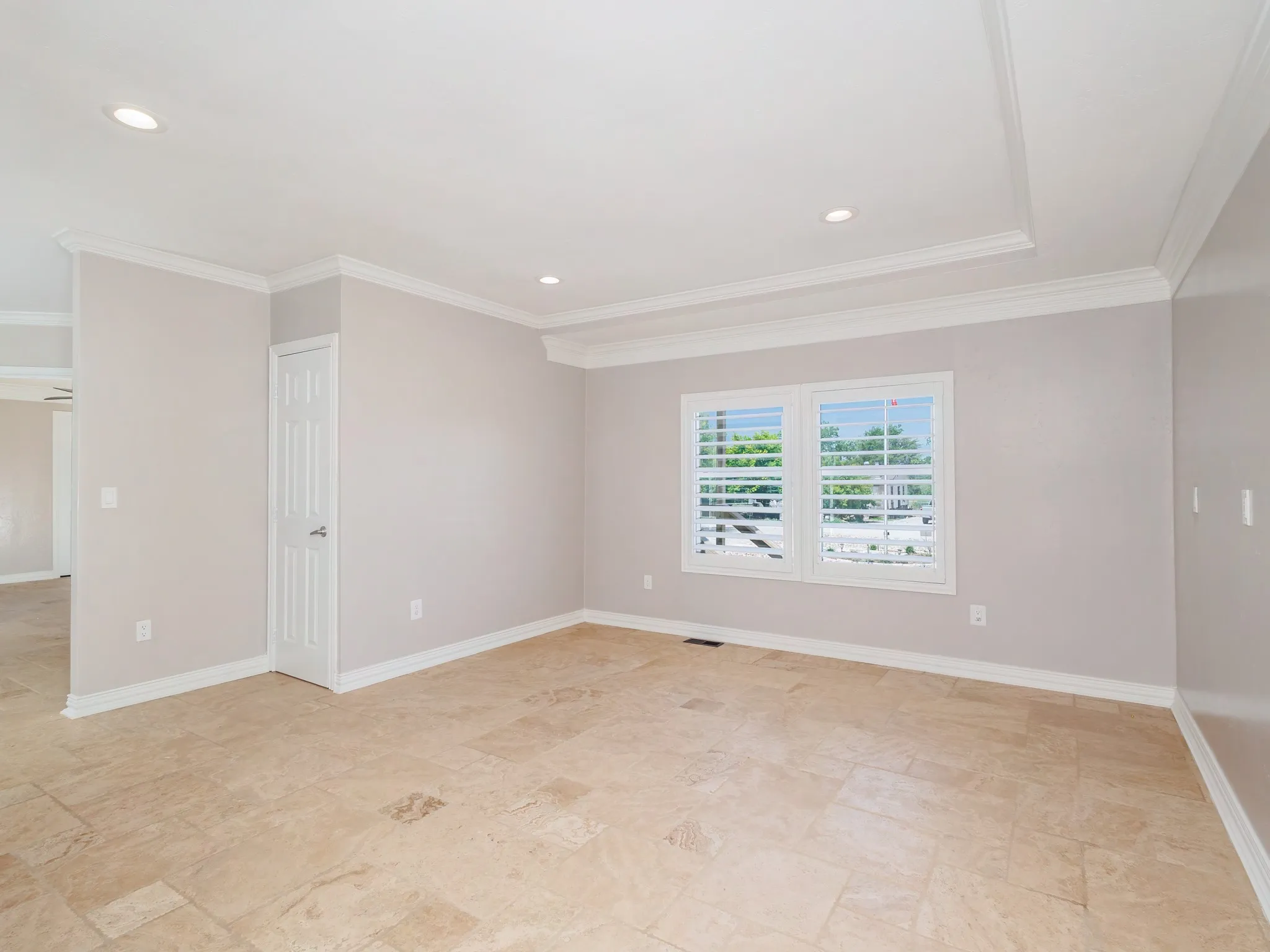Spacious room featuring neutral-toned tile flooring, white crown molding, and recessed lighting