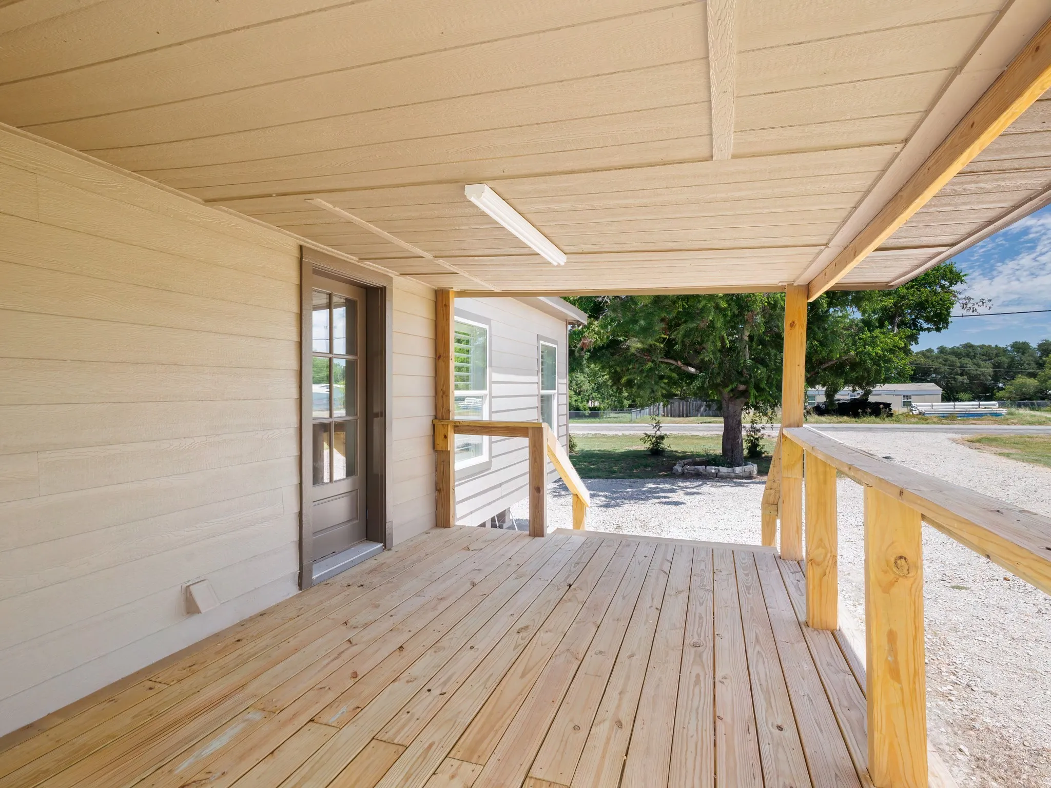 Covered porch featuring wood-finish decking, wood railing, and soffit ceiling with recessed lighting