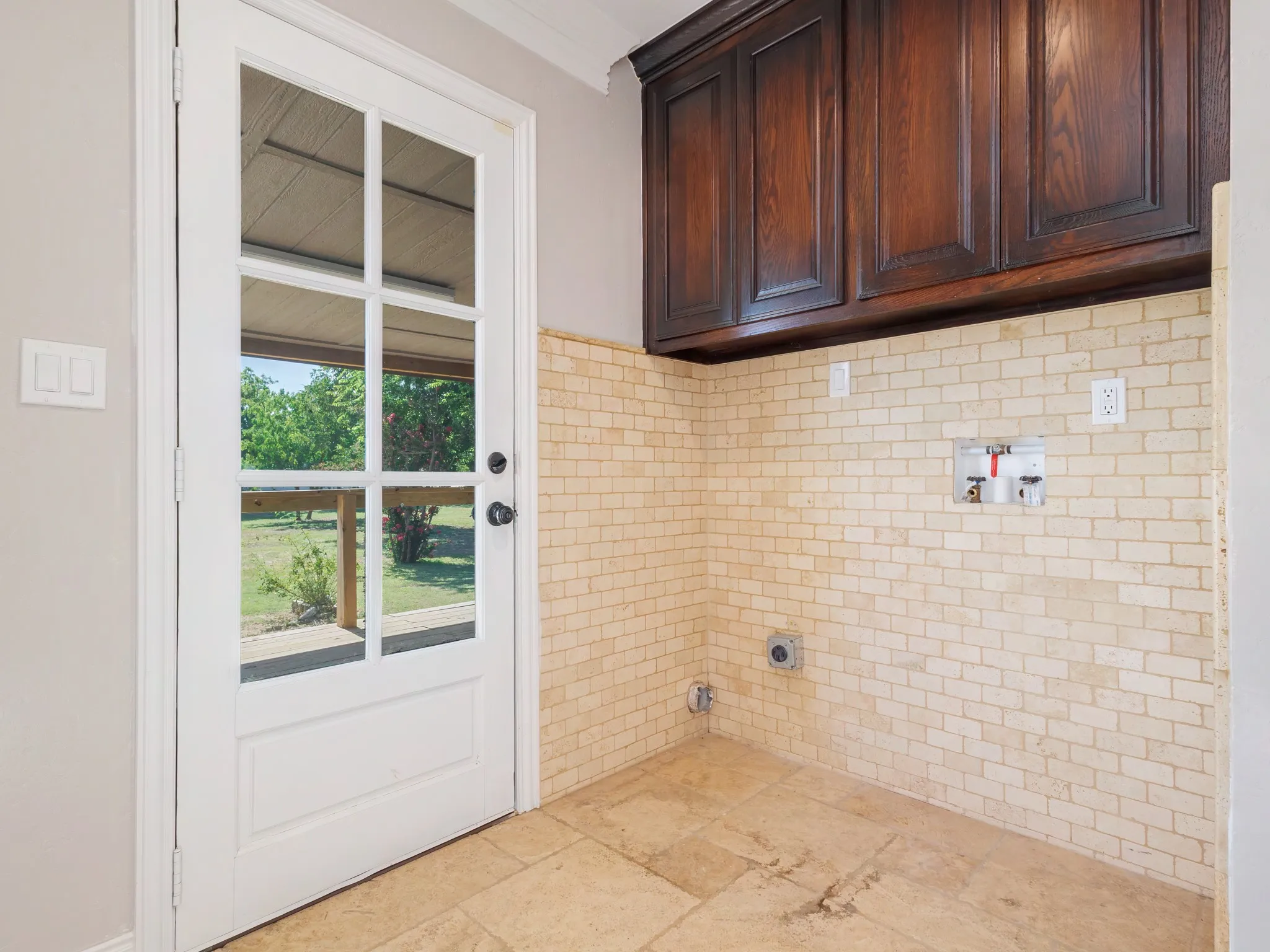 Utility area featuring rich wood-finish upper cabinetry and a subway tile backsplash