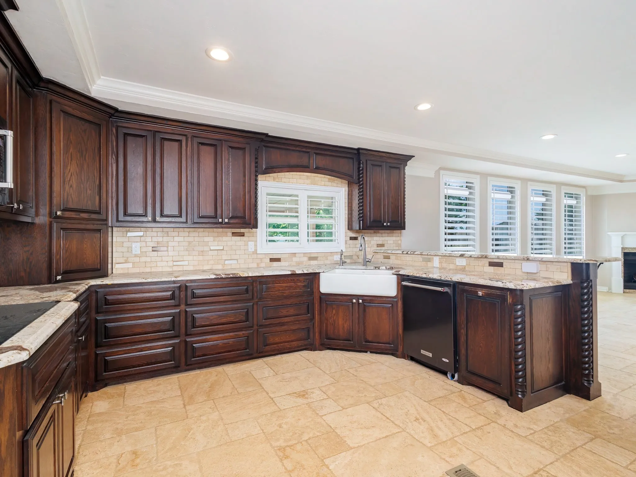 Kitchen featuring dark wood cabinetry, light-toned stone tile flooring, and a subway tile backsplash