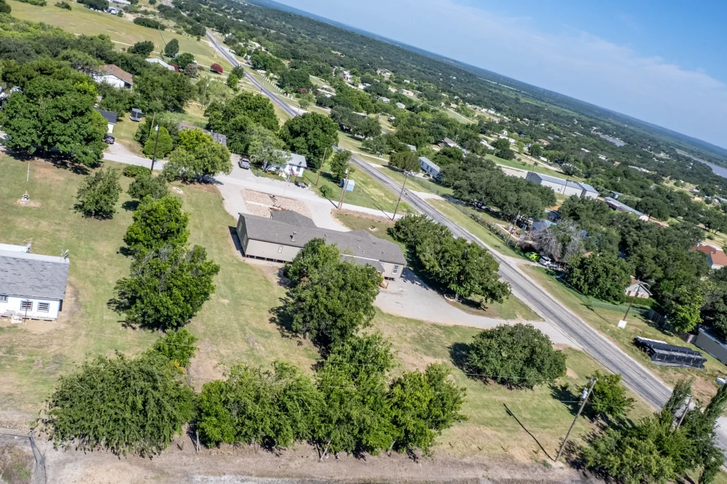 Aerial perspective showcasing a structure with a dark roof and light-colored siding, situated on a grassy lot