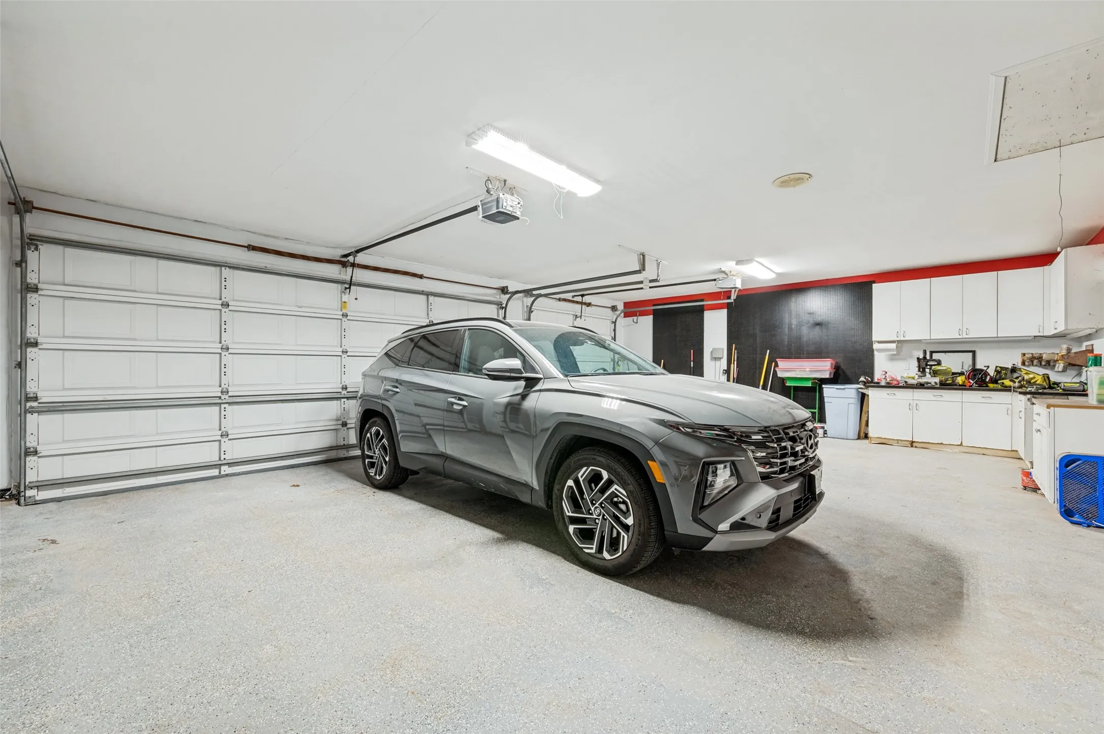 3 car garage is approx. 33 ft wide and 23 ft deep with pegboard, cabinets, shelves, vac system, solar panel controls, and doors to the attached shop.
