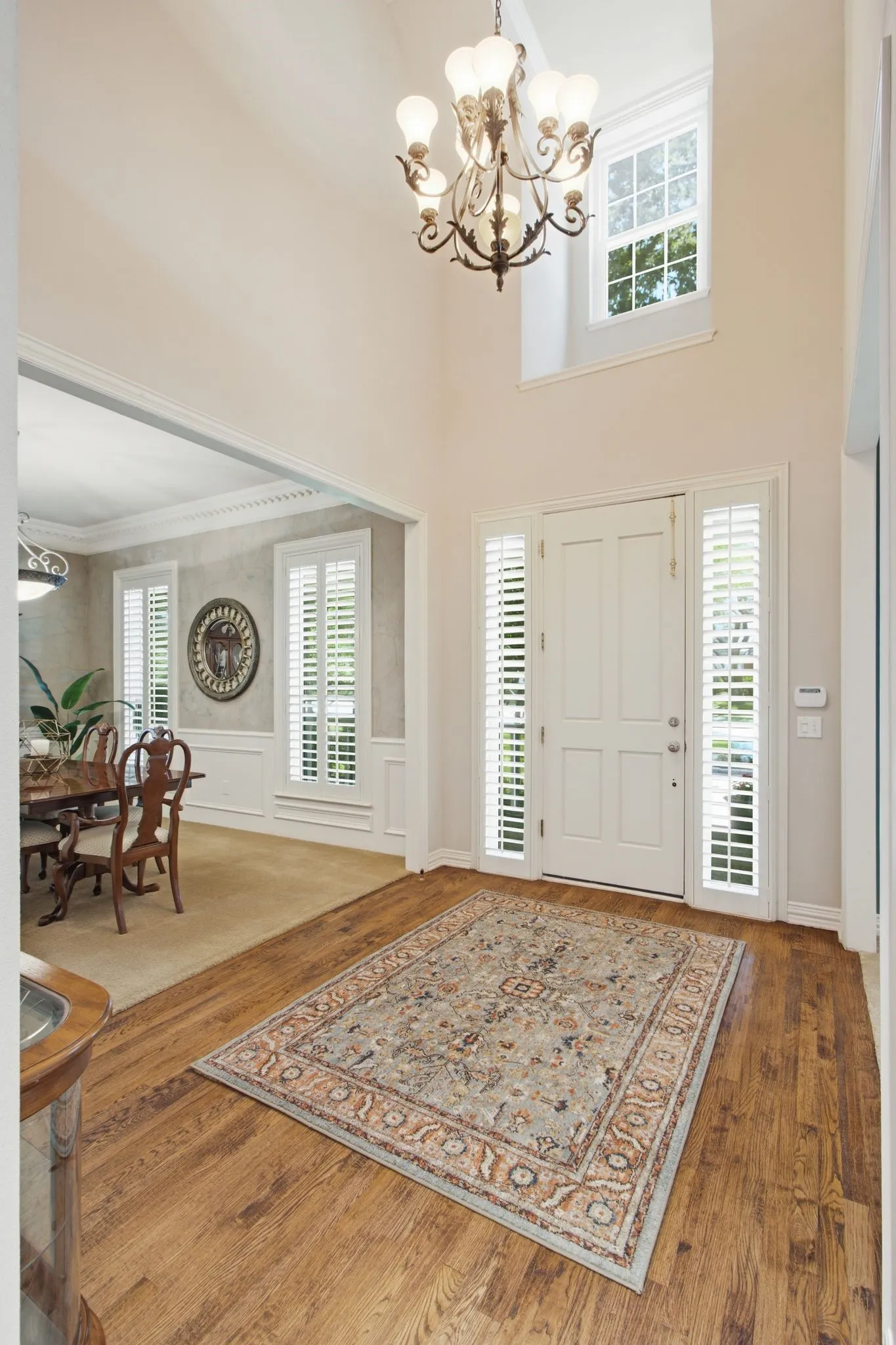 Double-height entry featuring wood-finish flooring, a decorative chandelier, and an elegant paneled front door with side lites
