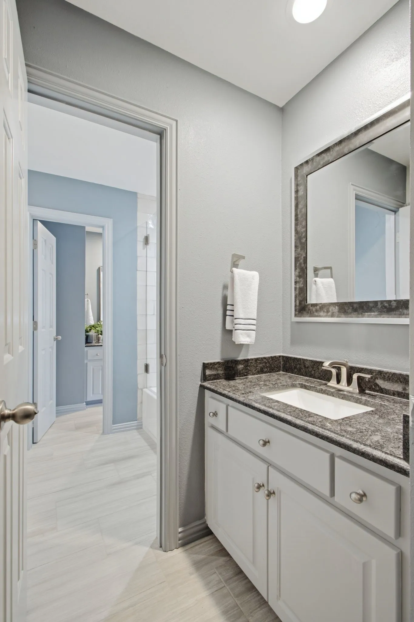 Vanity featuring a dark speckled countertop, undermount sink, and brushed nickel fixtures