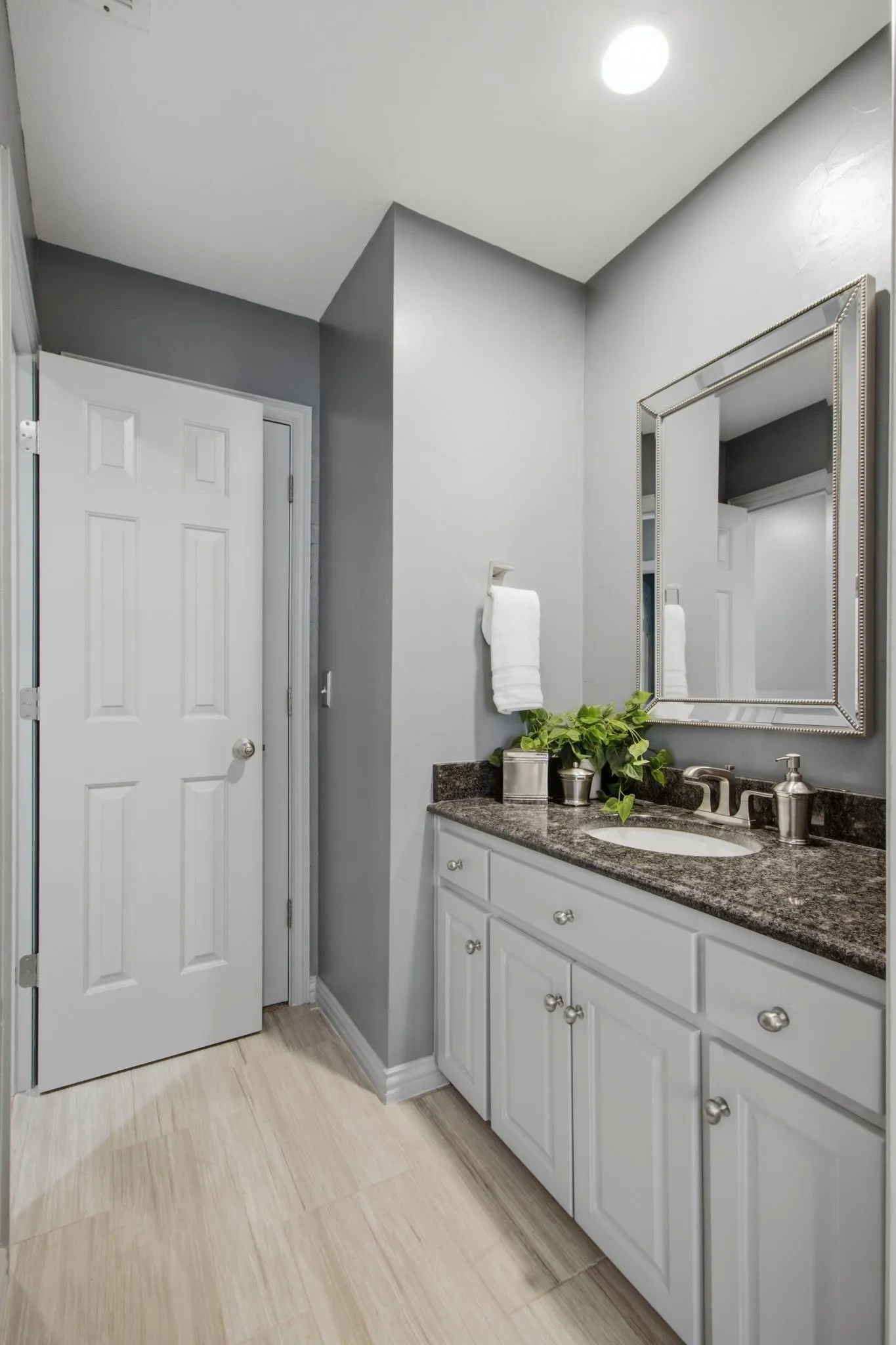 Bathroom vanity featuring white cabinetry with silver hardware, a dark speckled countertop, and an undermount sink
