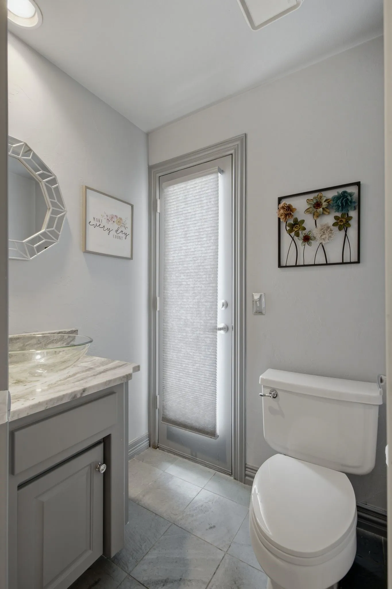 Powder room featuring a single vanity with a vessel sink, a light-toned countertop, and gray shaker-style cabinetry