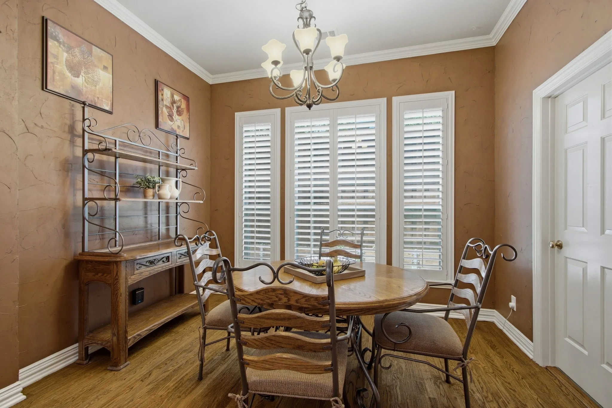 Formal dining area featuring wood-finish flooring, white crown molding, and plantation shutters