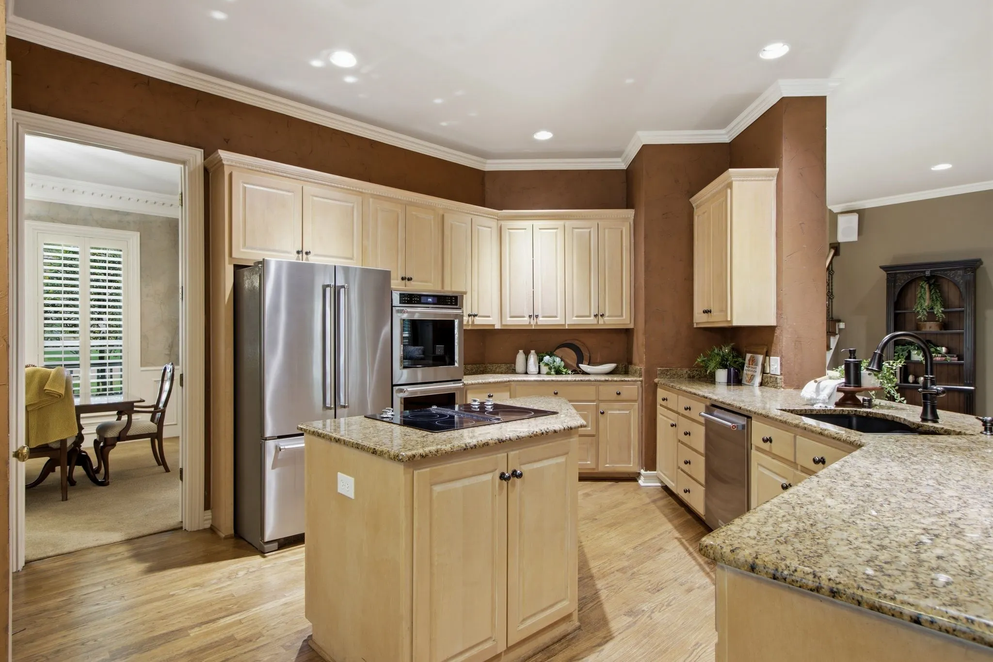 Kitchen featuring light wood cabinetry, stainless steel appliances, granite countertops, and wood-finish flooring