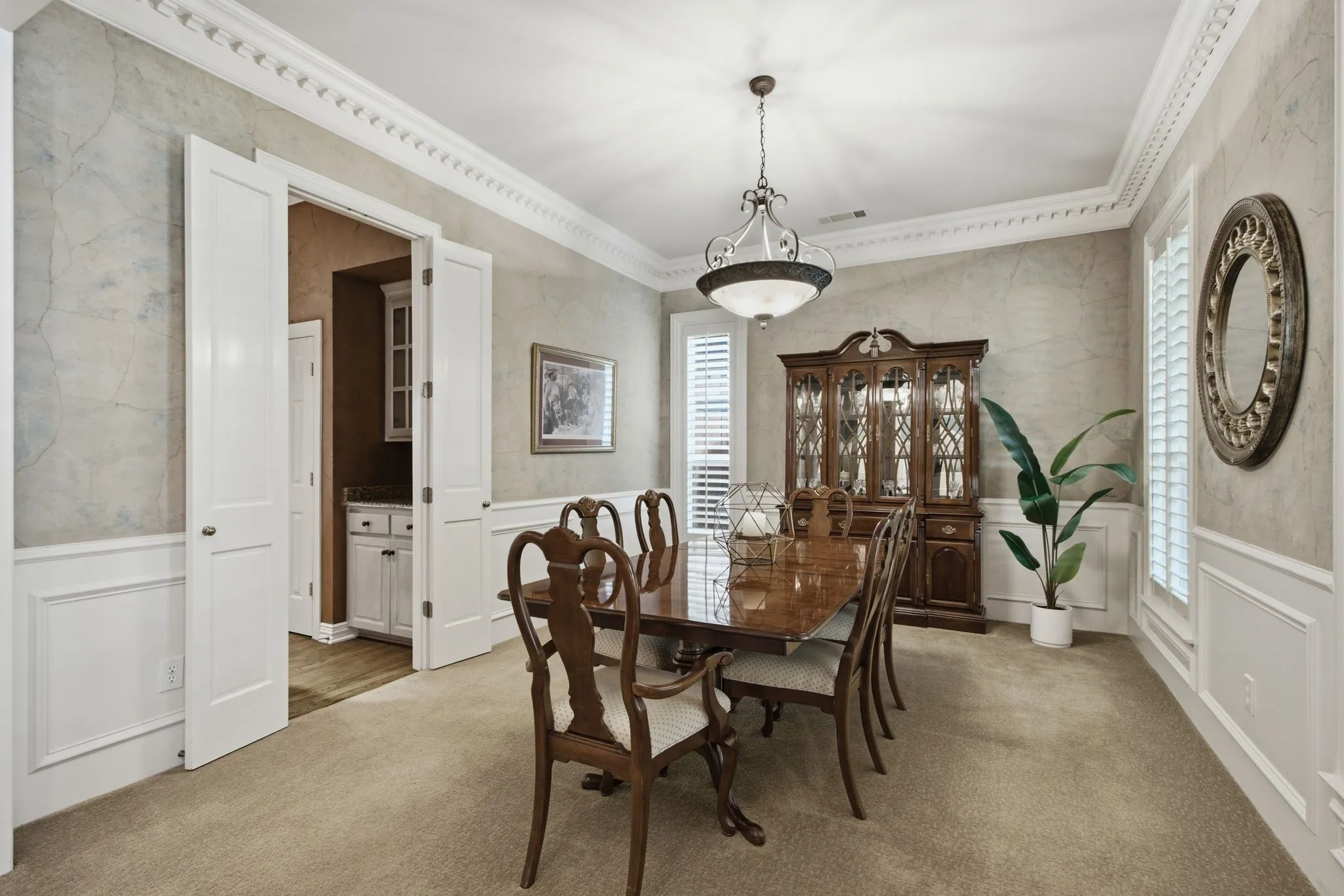 Formal dining space featuring intricate crown molding, wainscoting, and a central chandelier