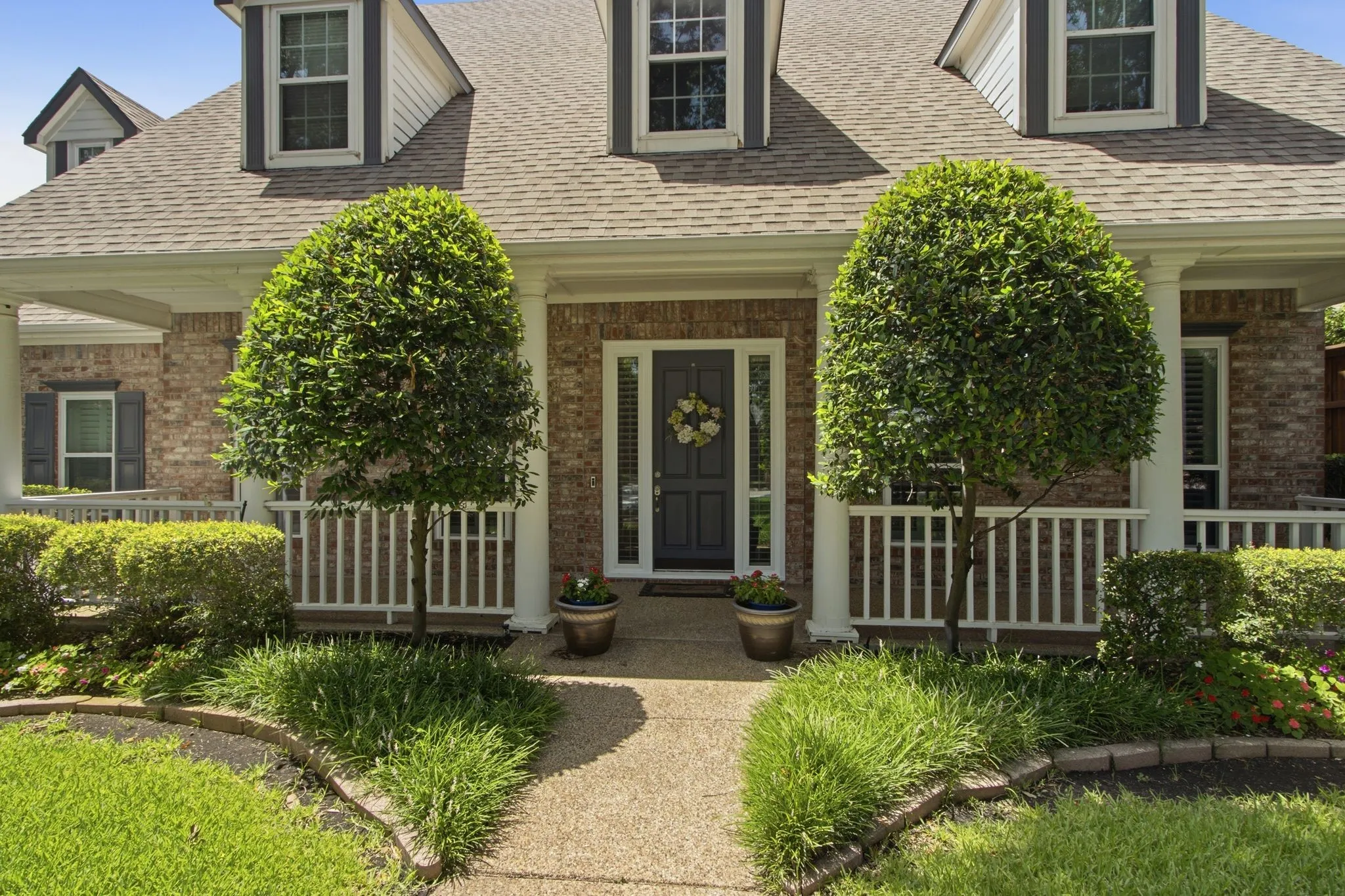 Brick exterior with white trim, dormer windows, covered front porch, and a gravel pathway