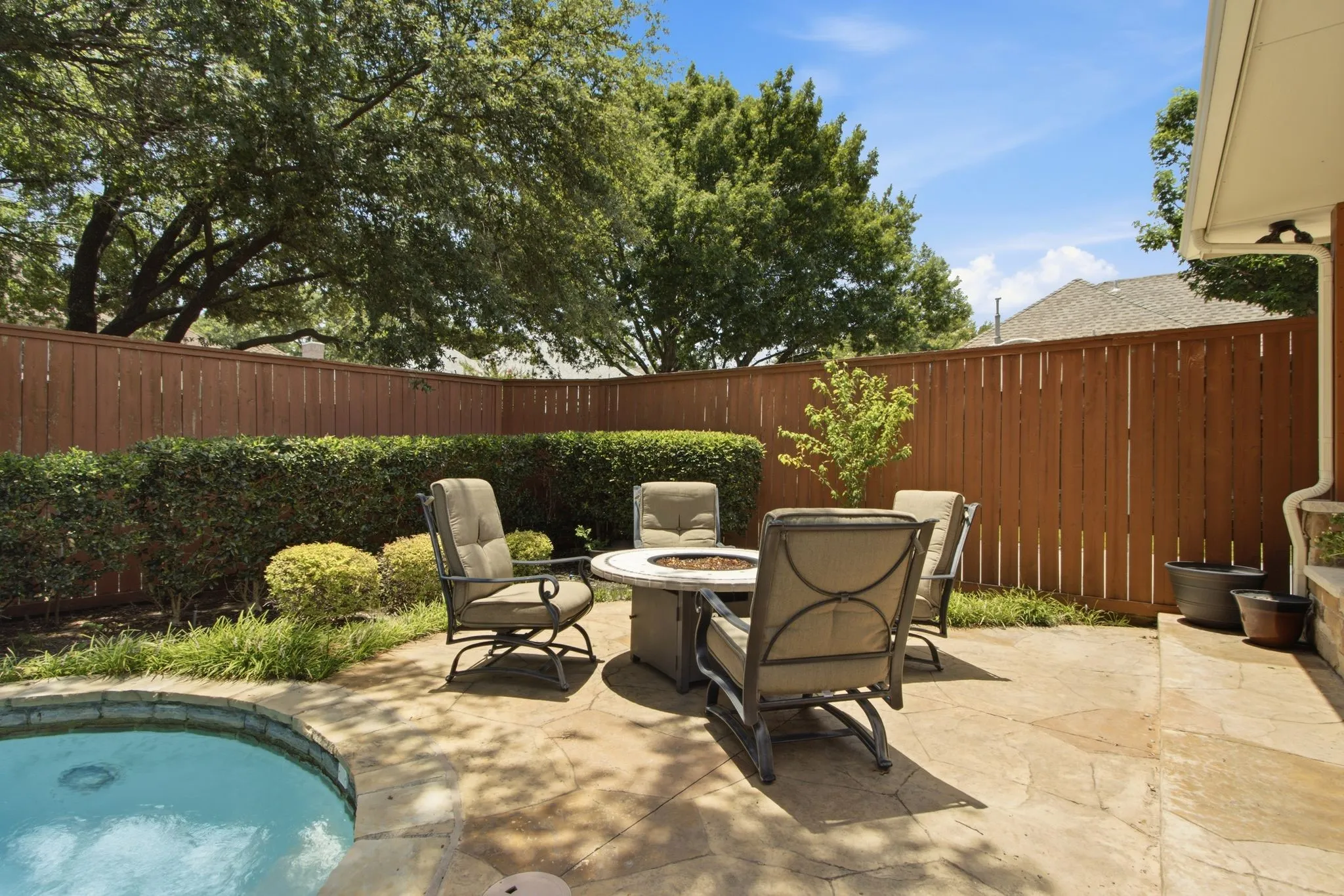 Private backyard featuring a curved pool, flagstone patio, and a privacy fence with mature landscaping