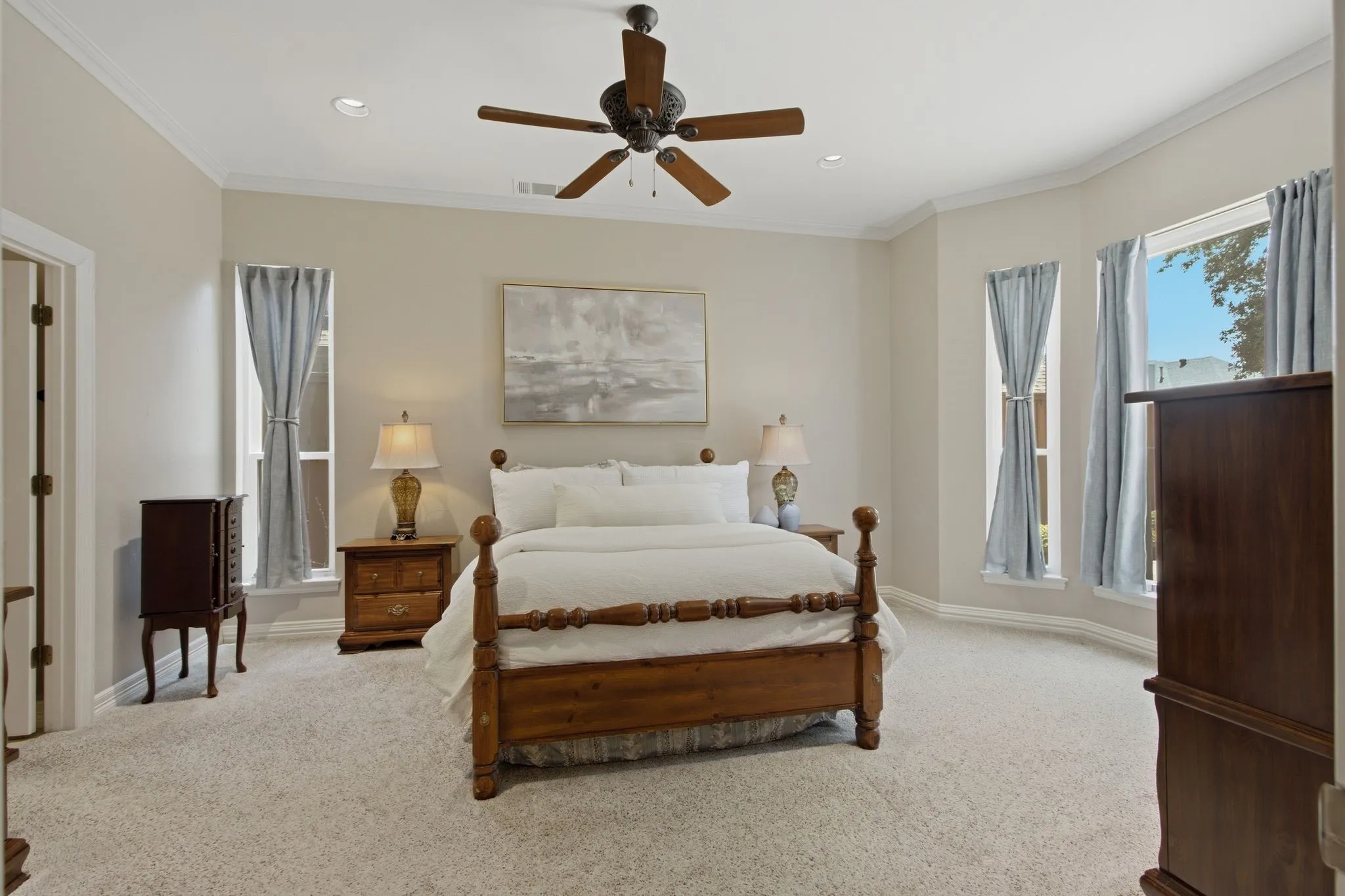 Spacious room featuring neutral carpeting, a tray ceiling with recessed lighting, and a ceiling fan