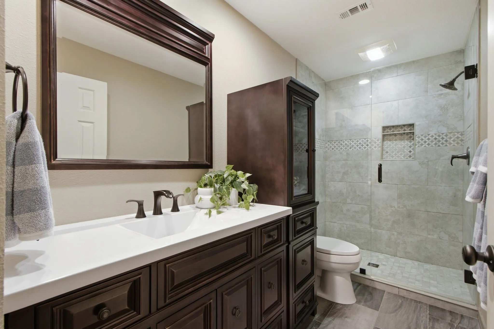 Full bathroom featuring a dark wood-finish vanity with ample storage, a white countertop with an integrated sink, and an oil-rubbed bronze faucet