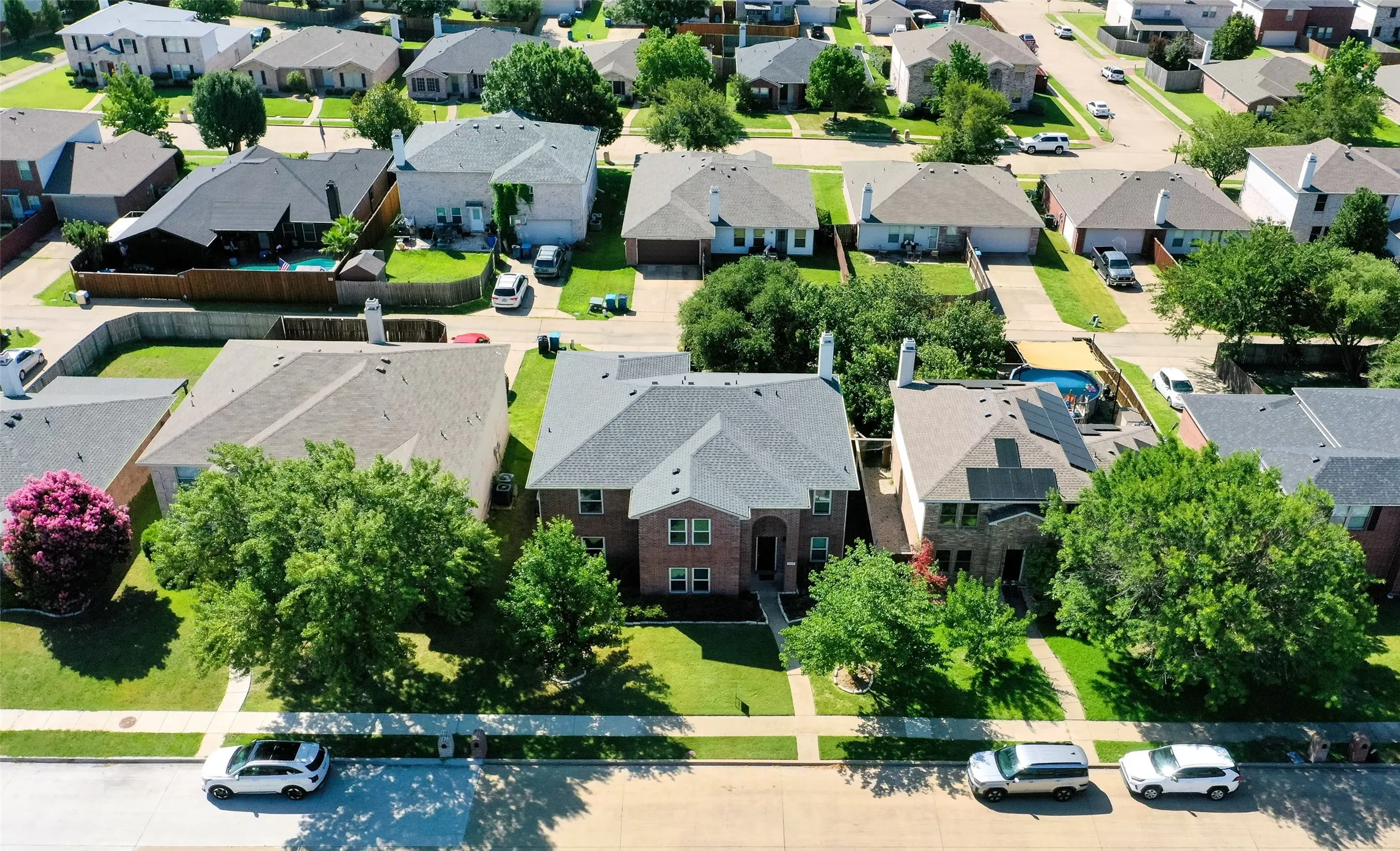 Two-story brick exterior with a gabled roof and mature front yard trees