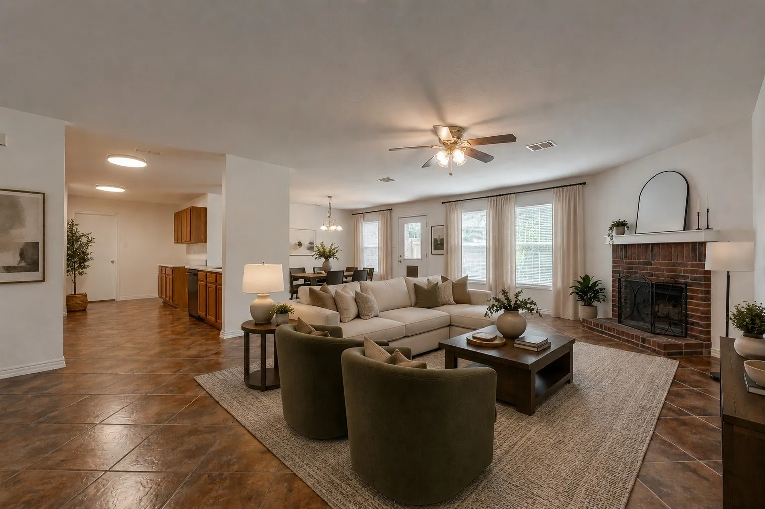 Spacious living area featuring a prominent brick fireplace, multiple windows with natural light, and a ceiling fan